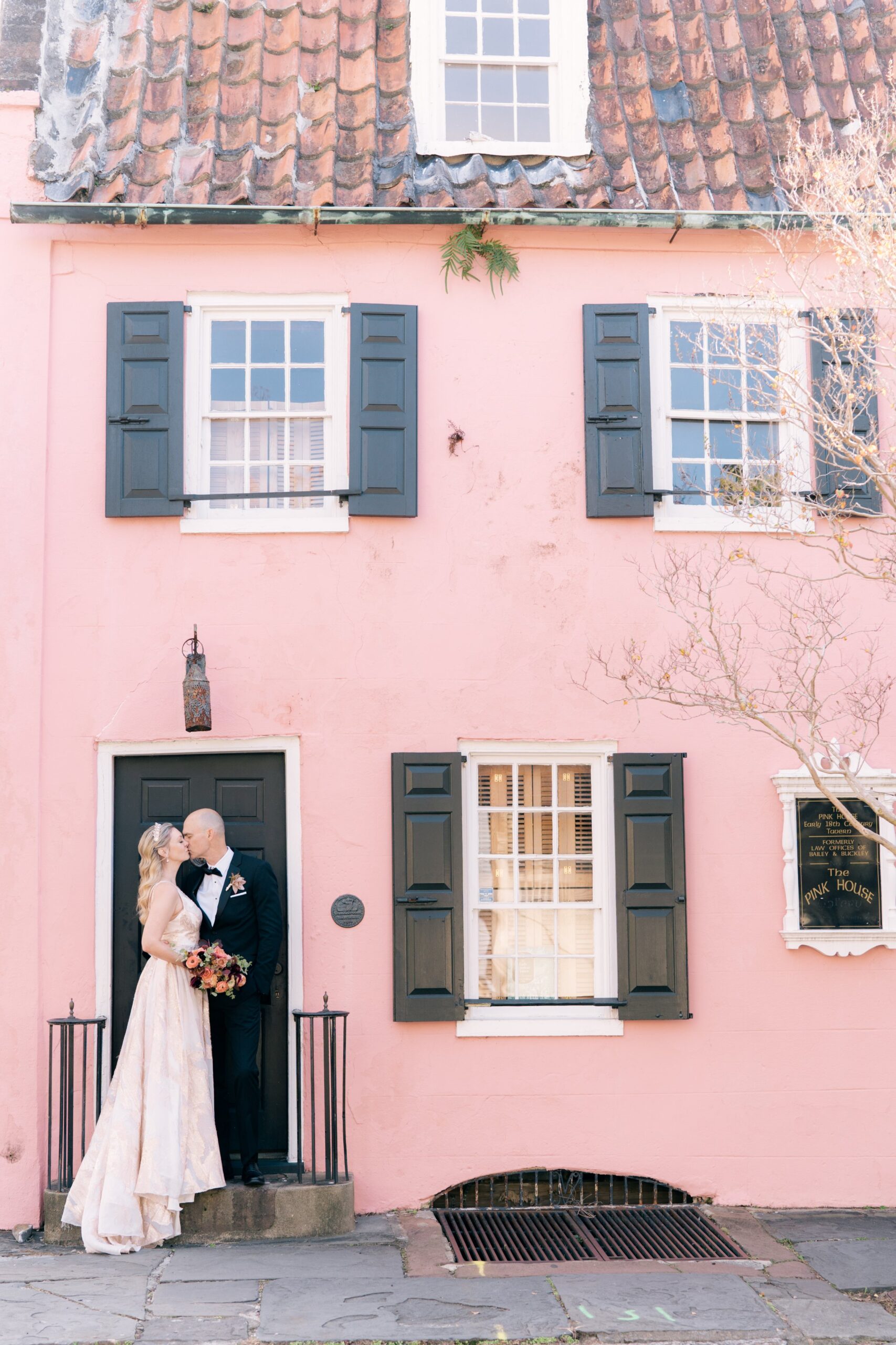bride and groom kiss on steps of historic pink building