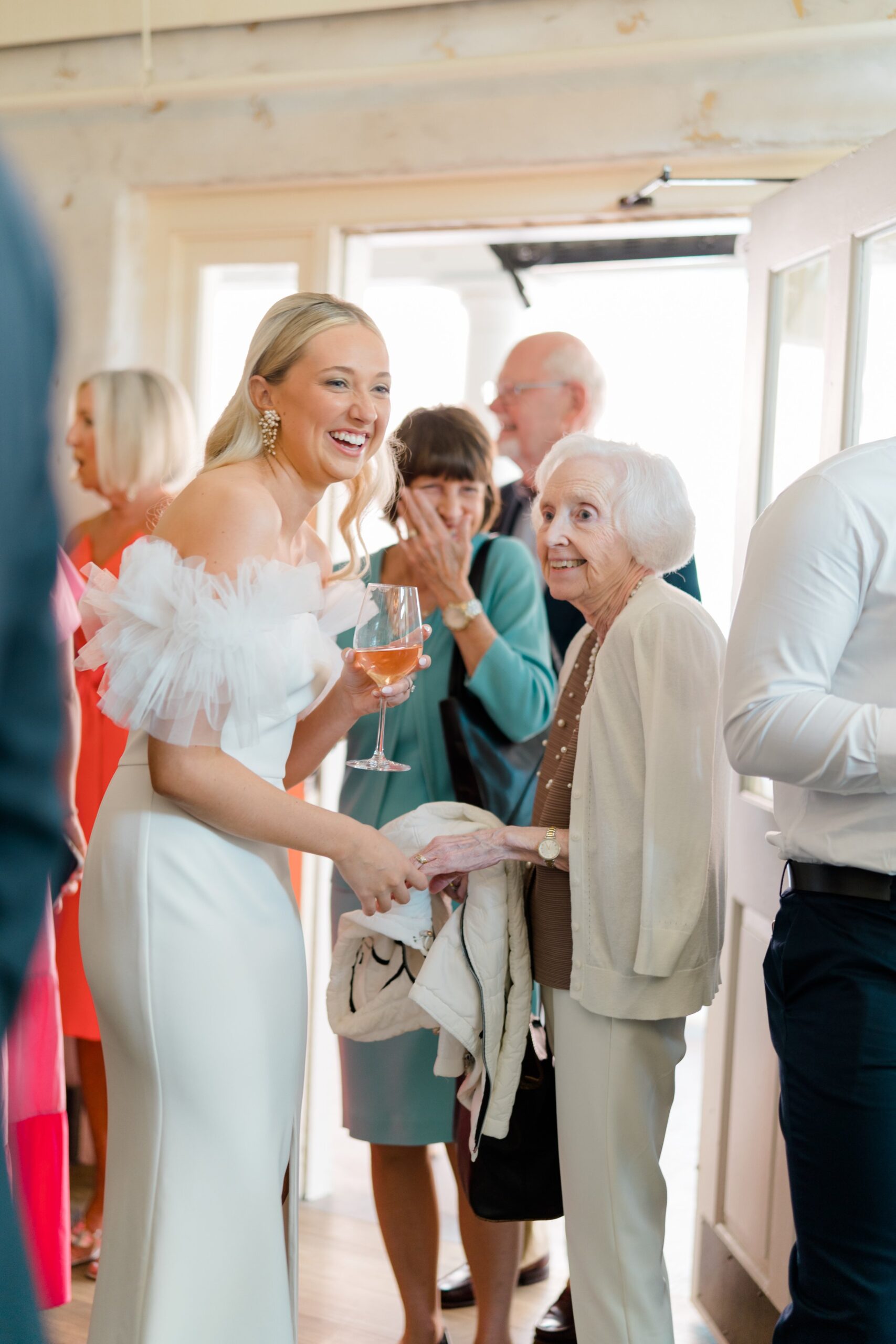 bride shares fun moment with grandmother. Bride with puffy tulle sleeved dress. rehearsal dinner dress ideas.