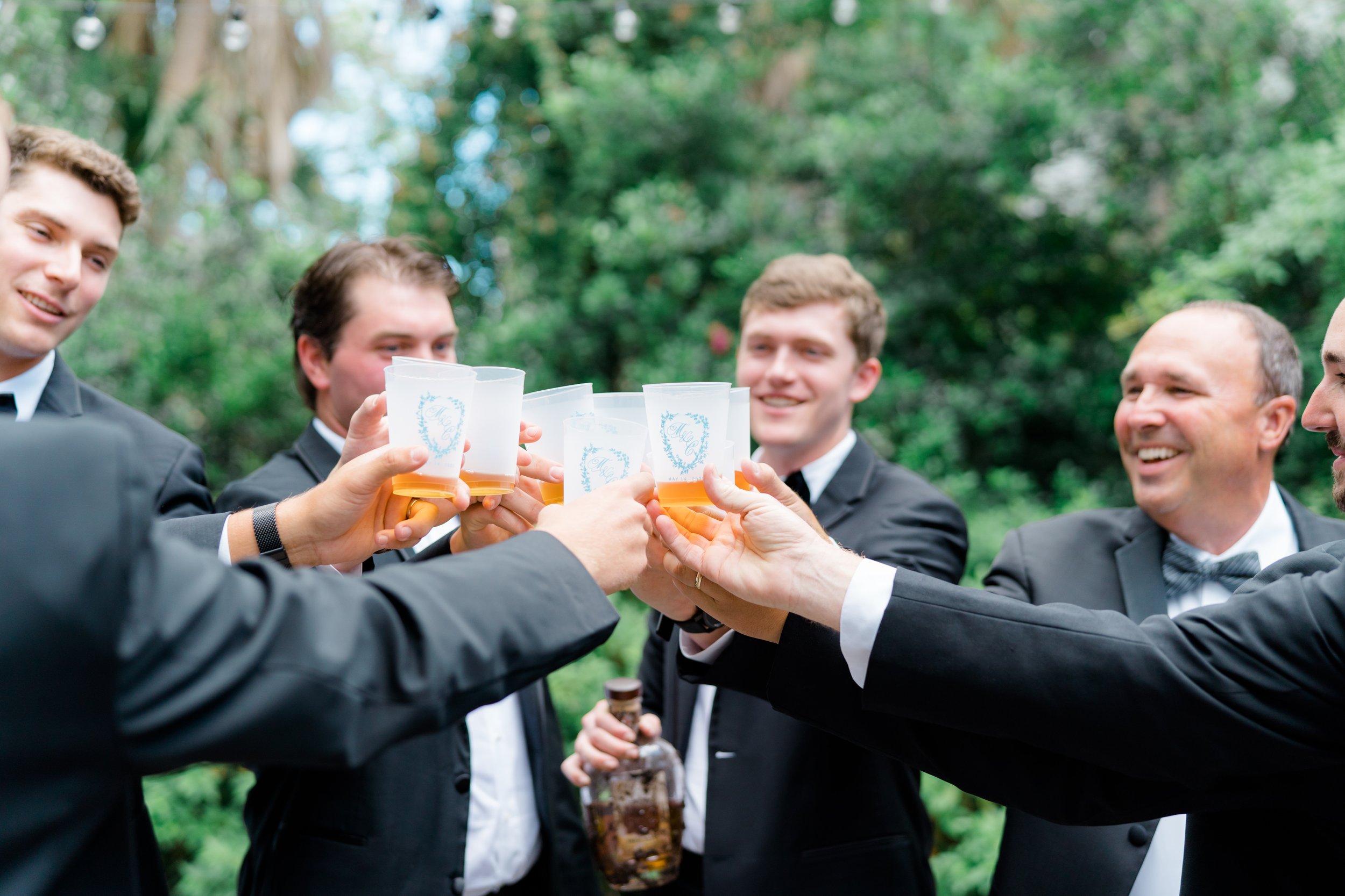 Groomsmen bourbon toast in custom wedding day cups.