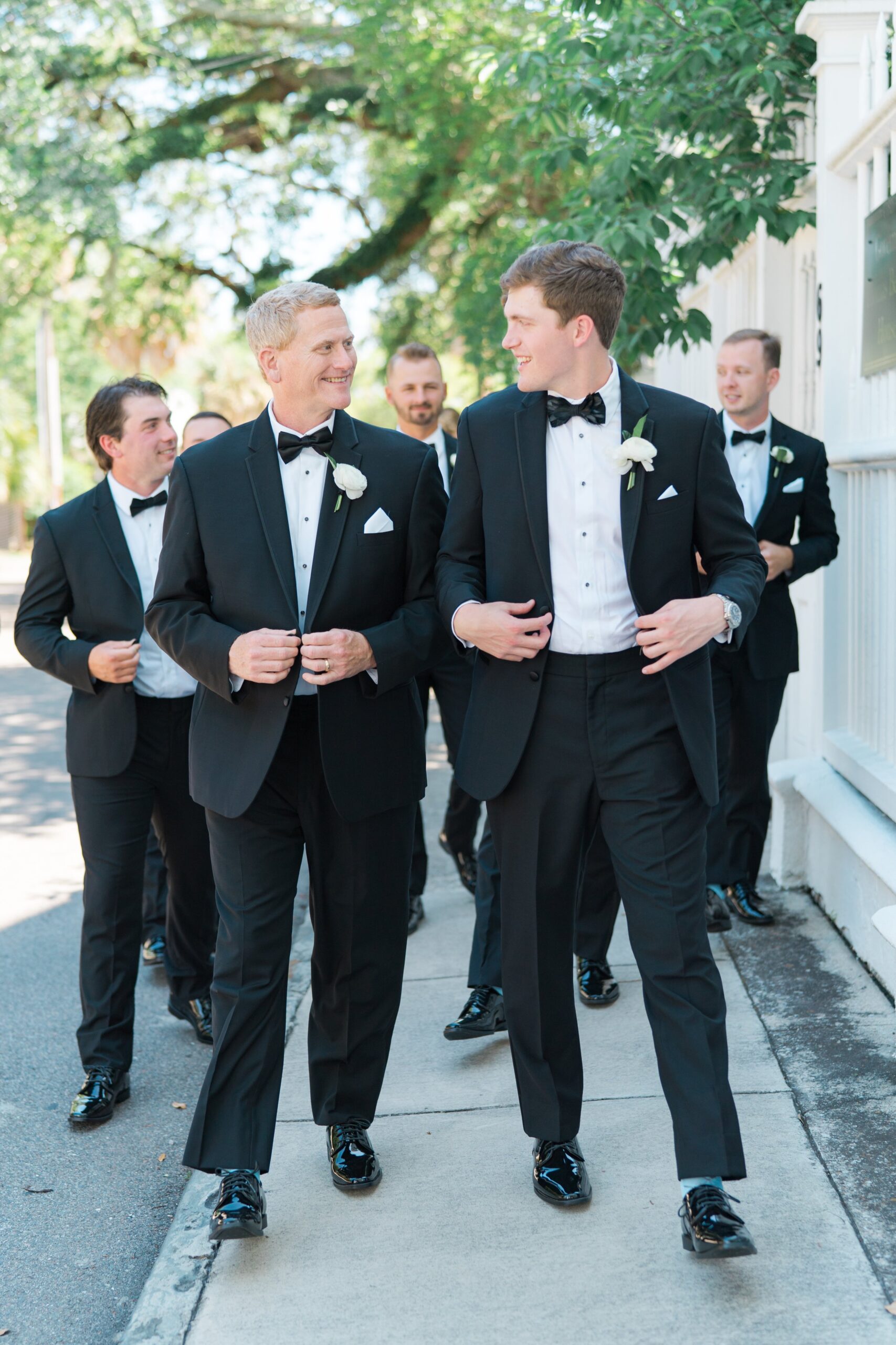 Groom walking with groomsmen. Black tuxedo with light blue socks.