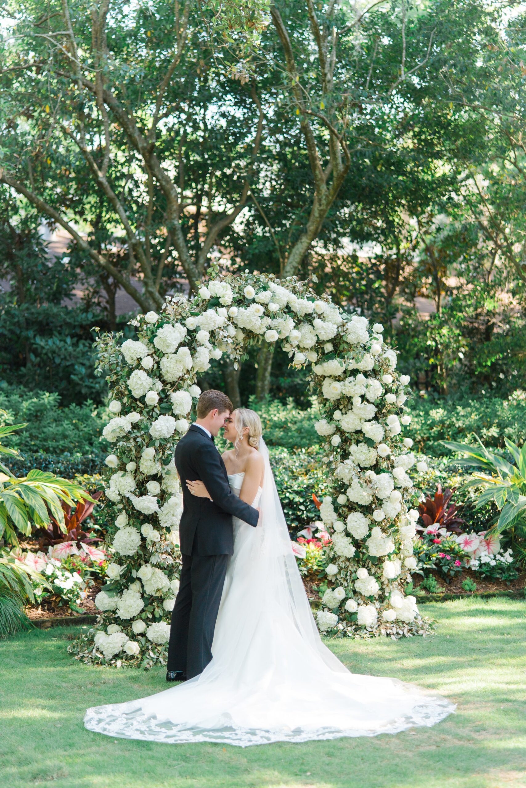 Bride and groom in front of floral arch. East Coast Destination Wedding Photographer.