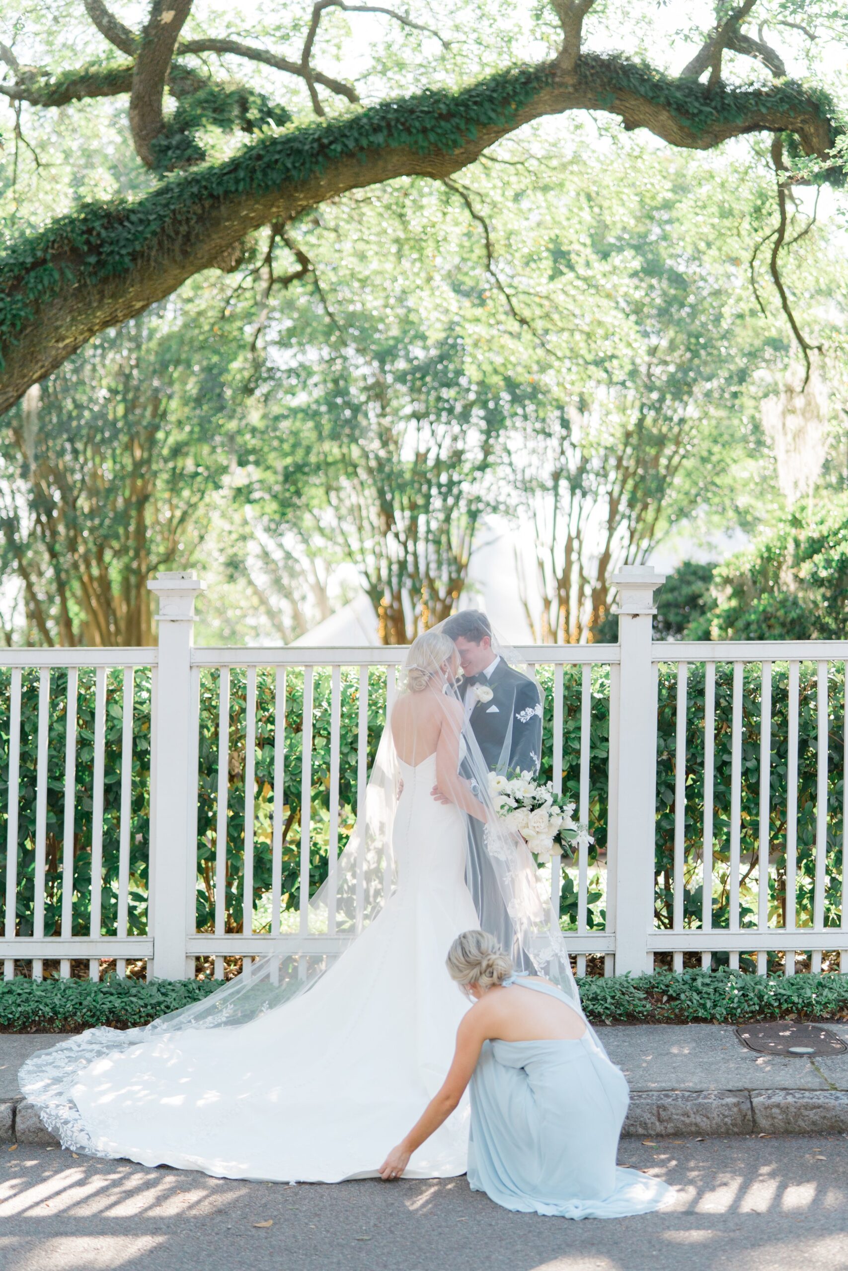 Bridesmaid helps with veil at downtown Charleston wedding. Charleston wedding photographer.