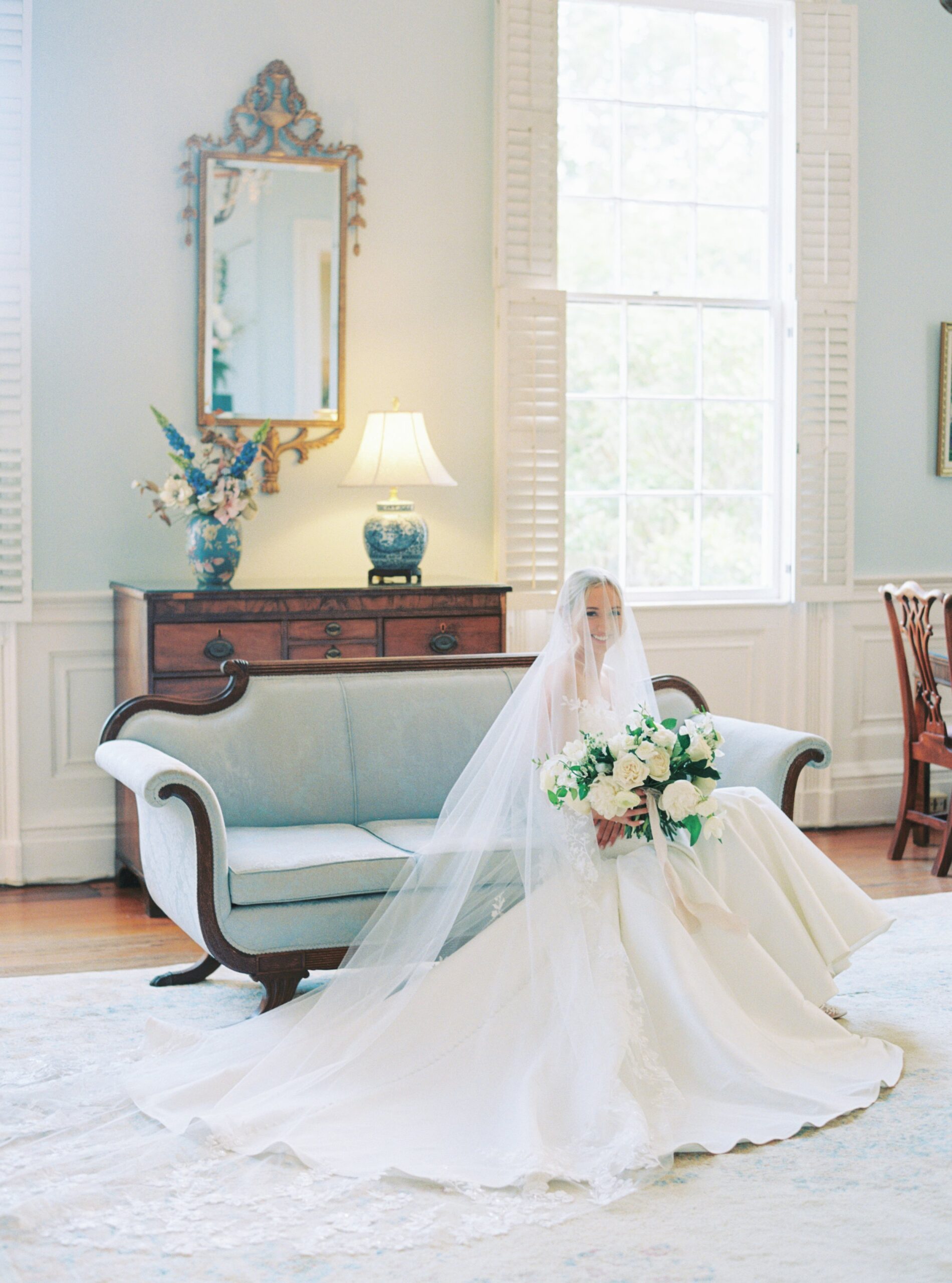 Light blue vintage couch in light blue room with bride covered in flower detailed veil. Thomas Bennett House wedding.