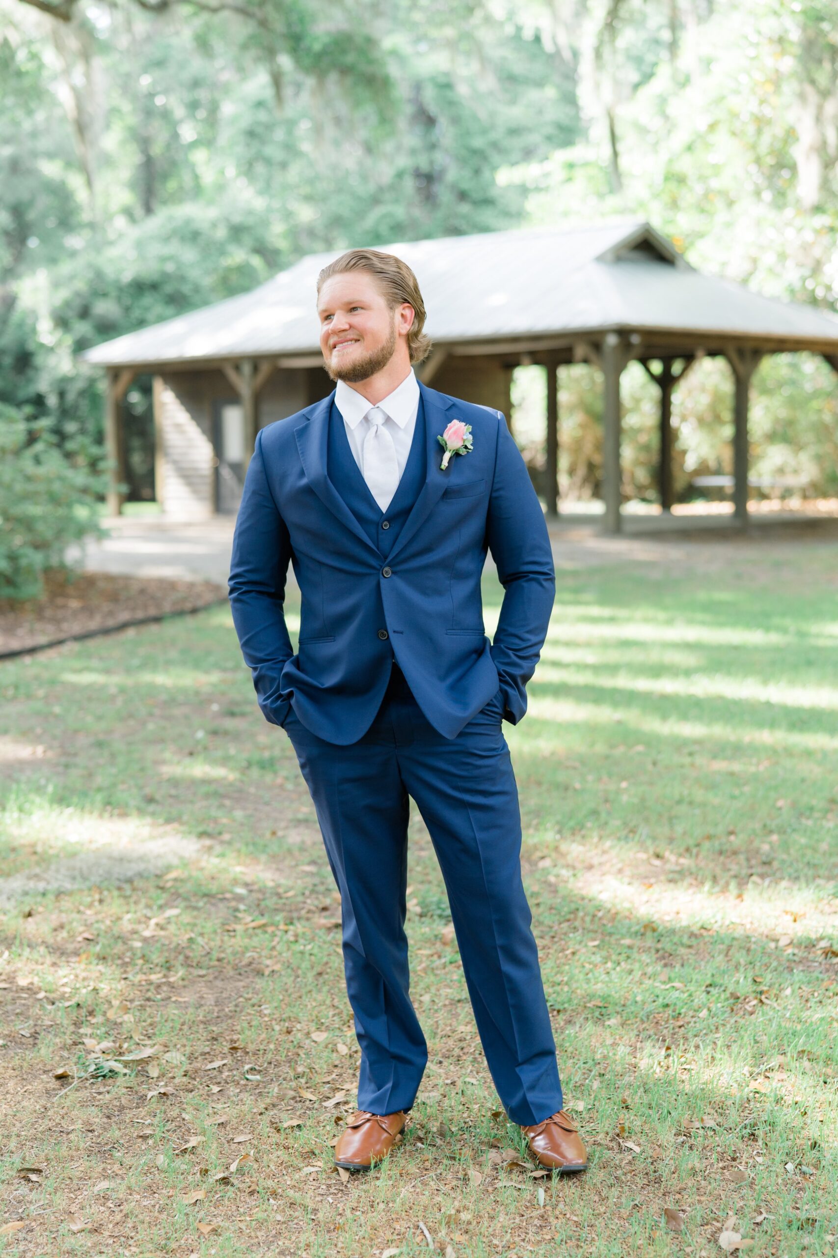 groom in three piece blue suit and white tie
