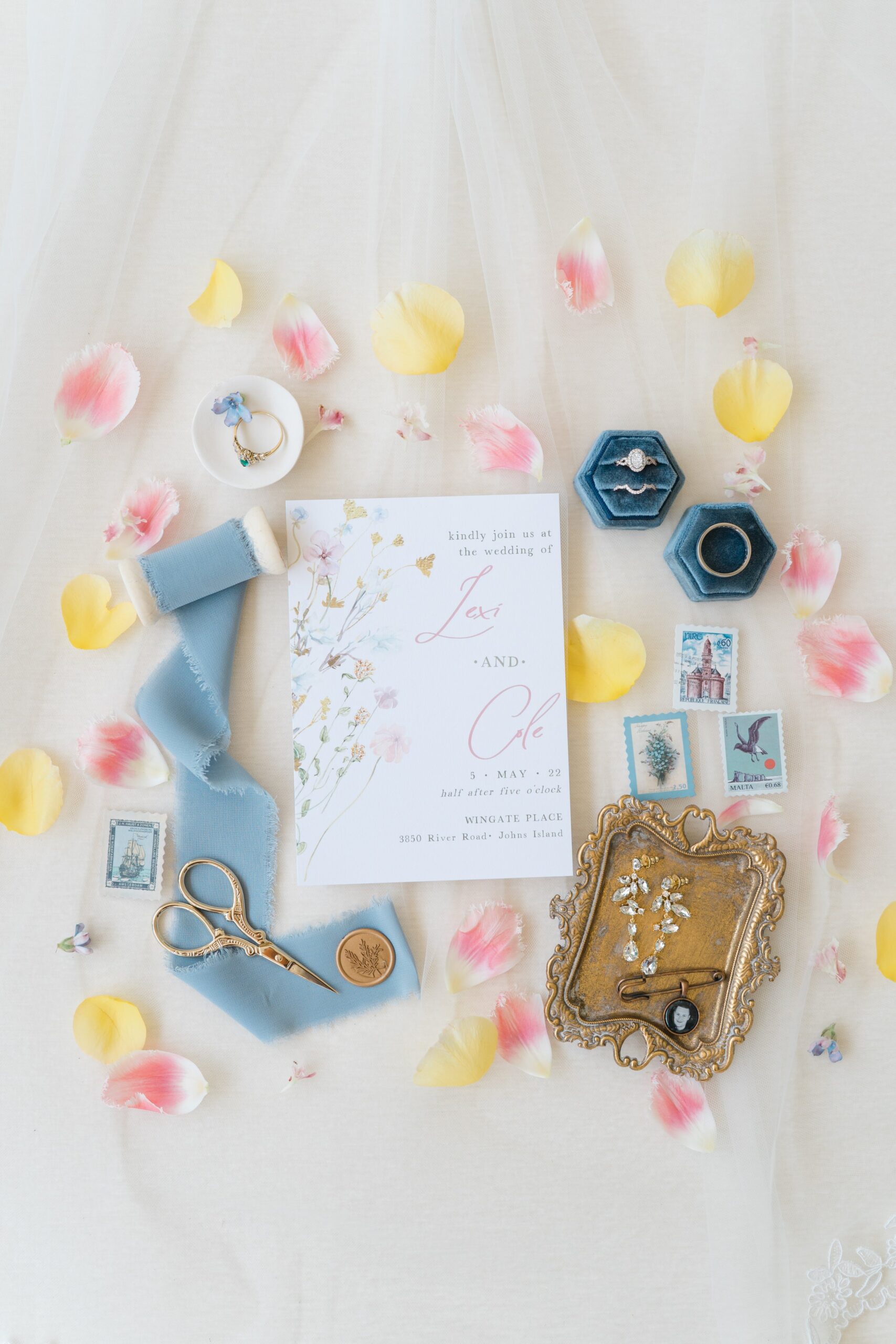 wedding invitation with flower petals and blue ribbon
