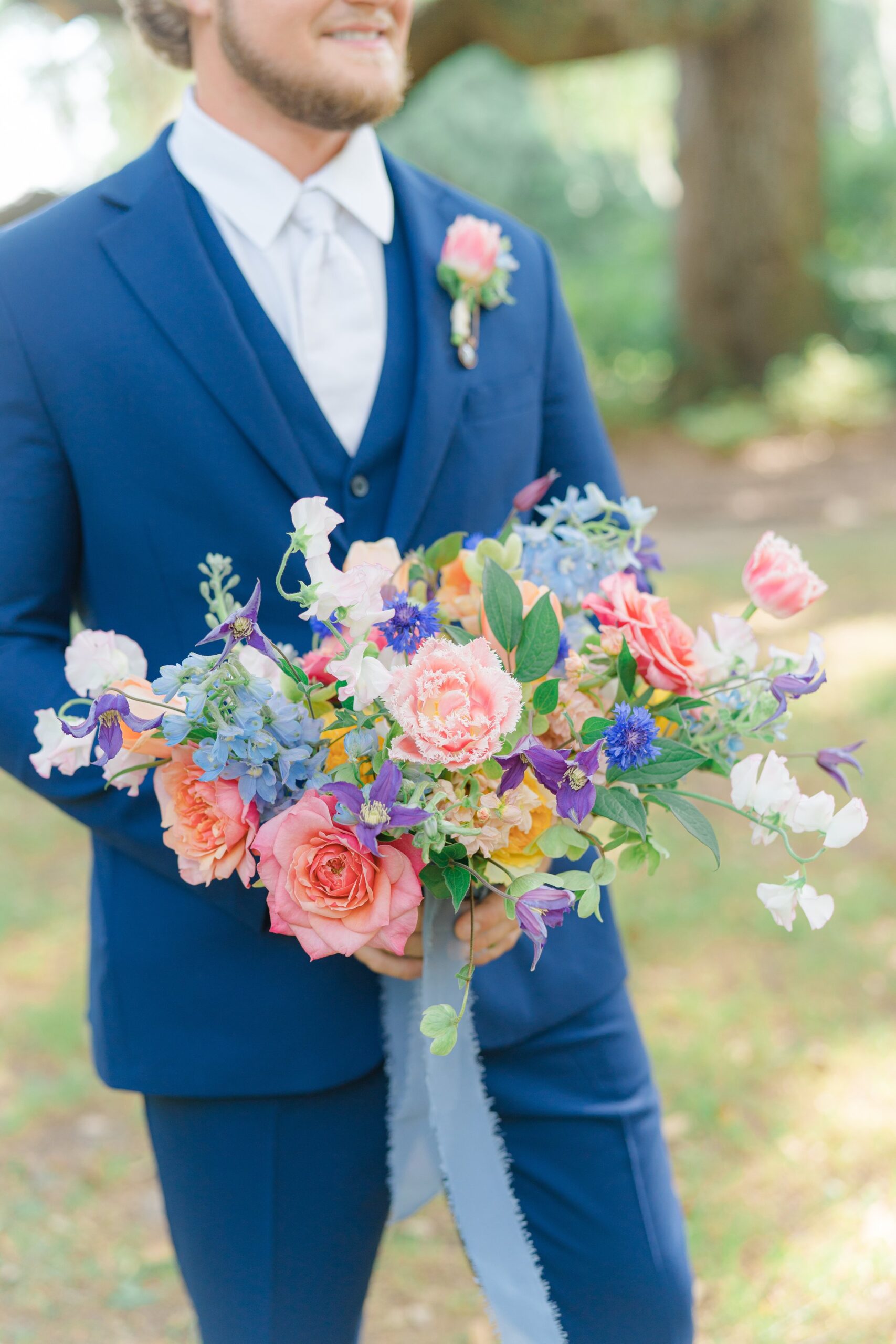 groom holding brides colorful flowers