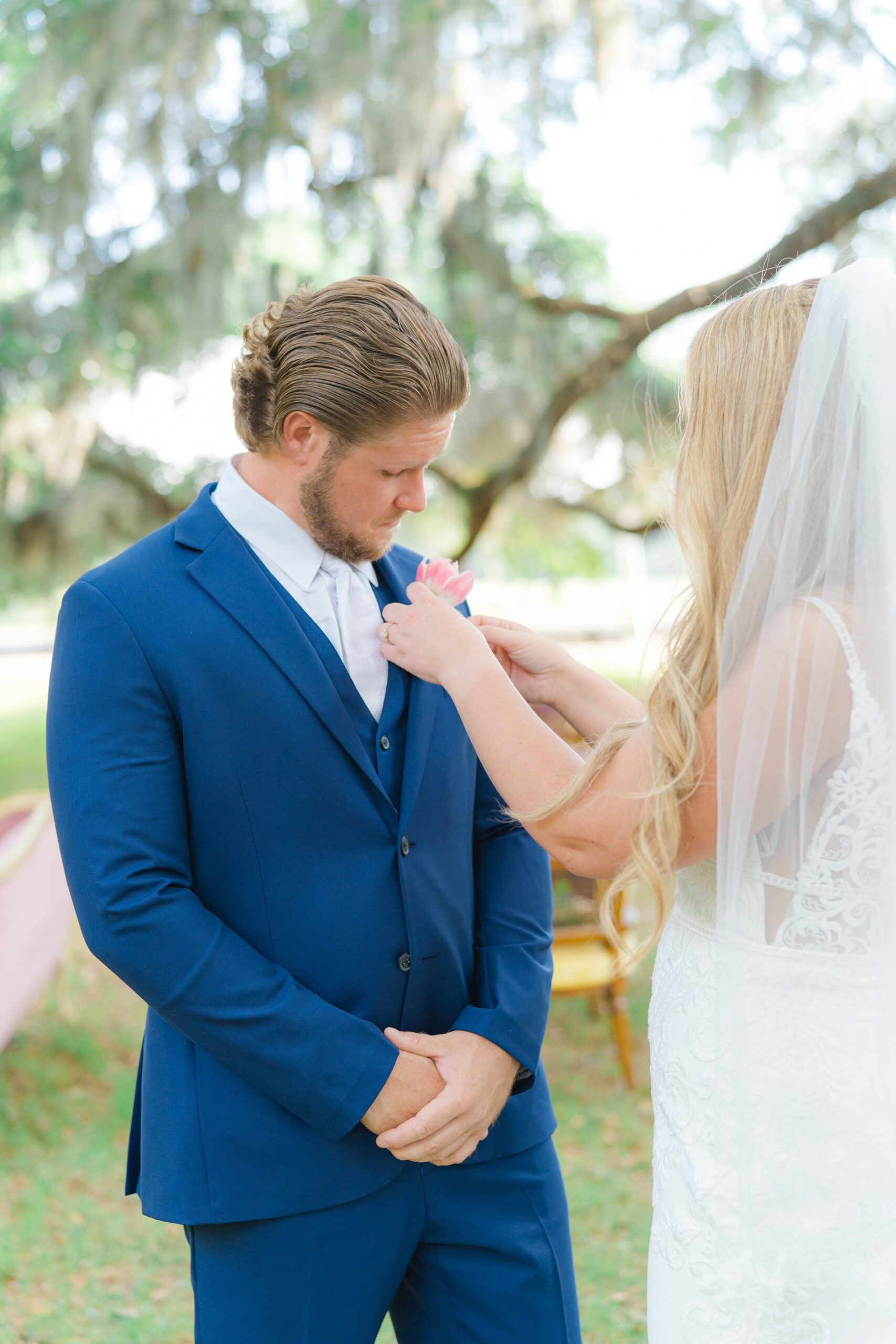 bride helping groom with pink boutonniere