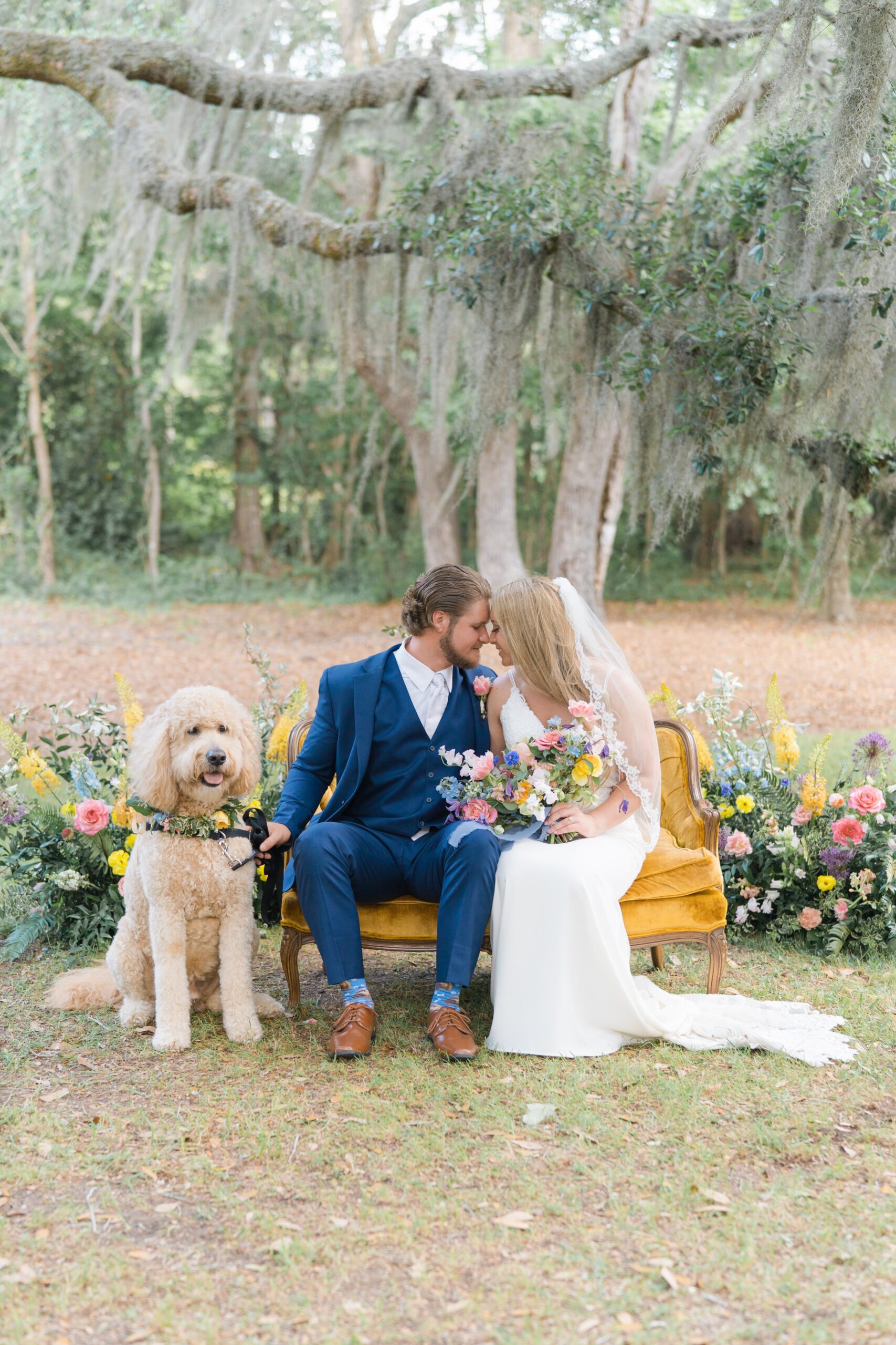 bride and groom sit on yellow vintage couch with doodle and wildflowers