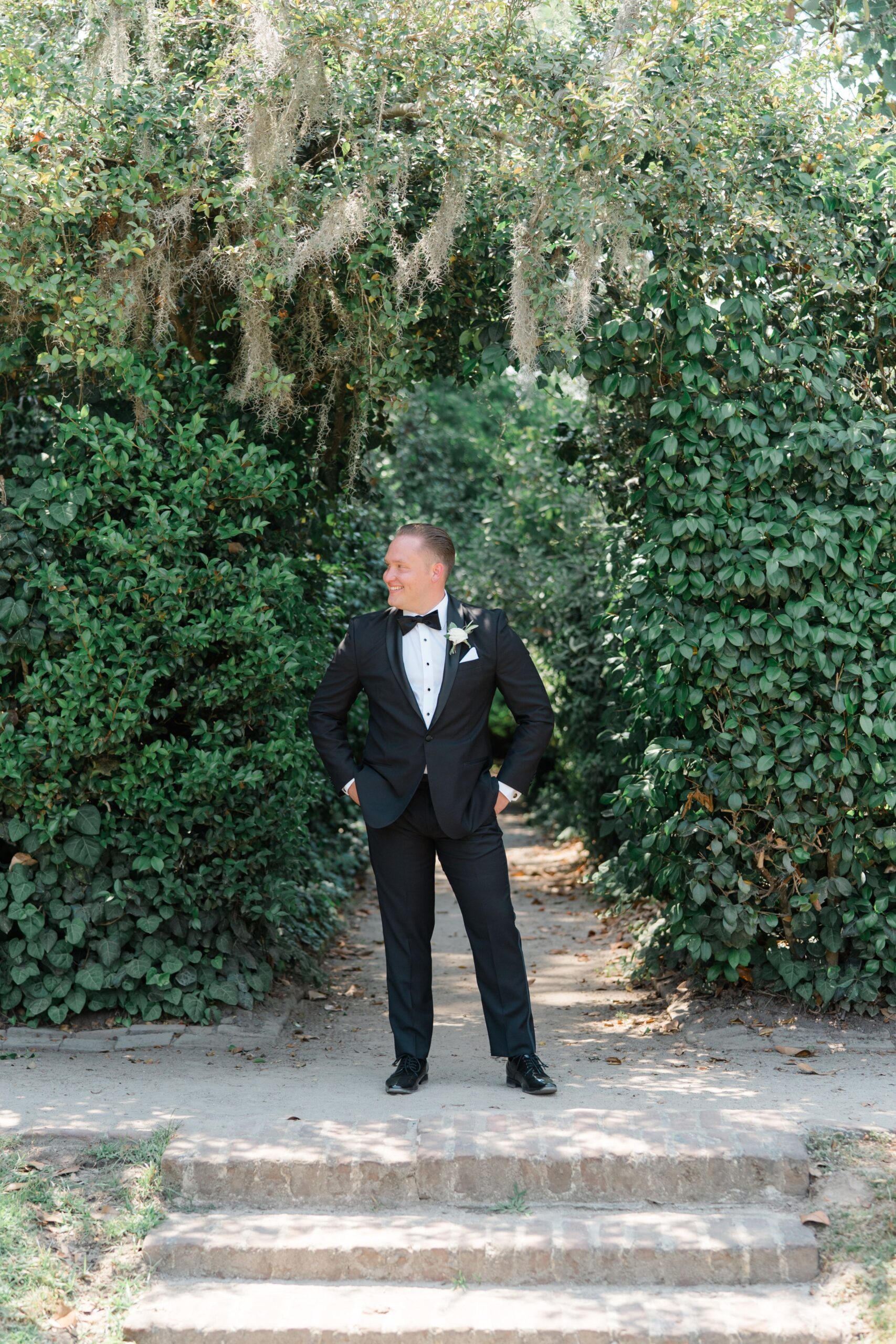 Black tie Charlesotn spring groom standing at secret garden entrance.