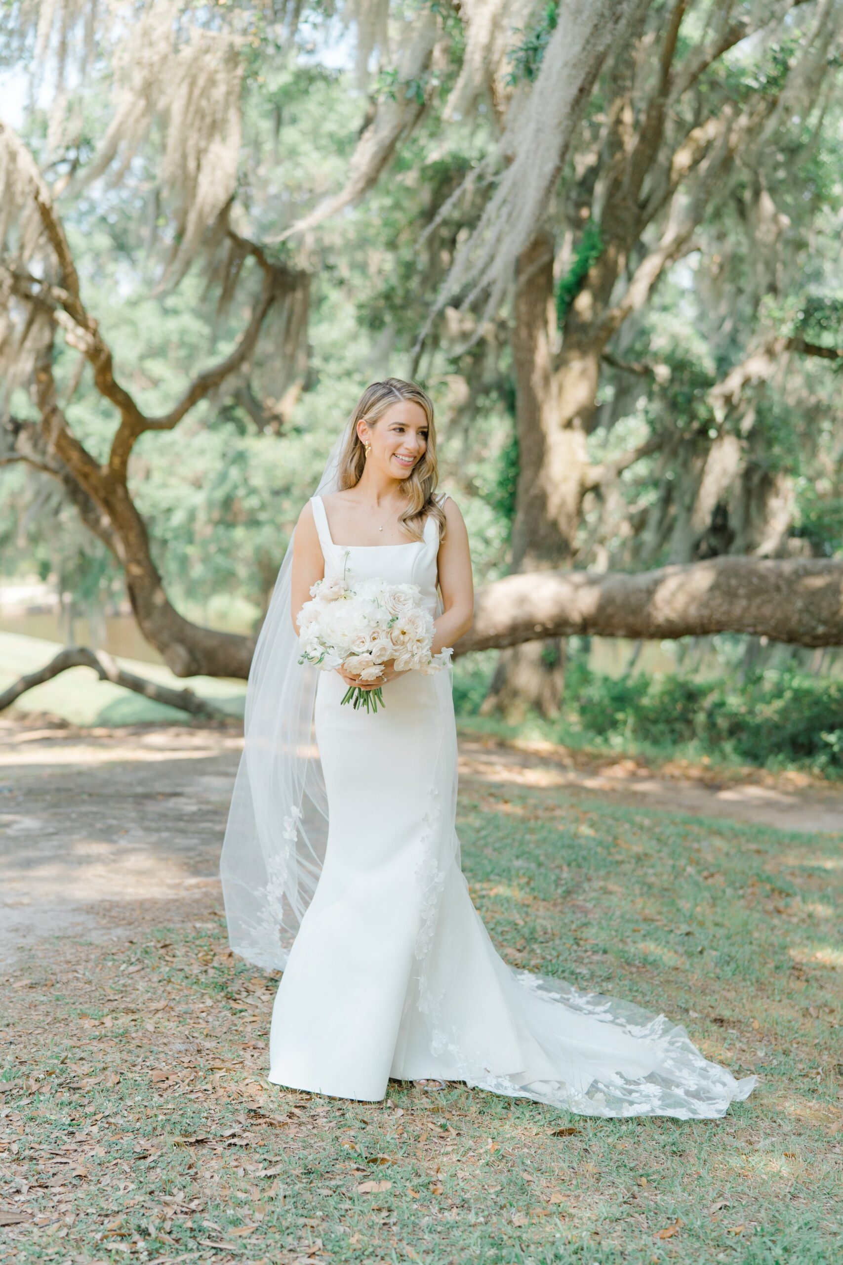 Bride standing in front of live oak trees and spanish moss.