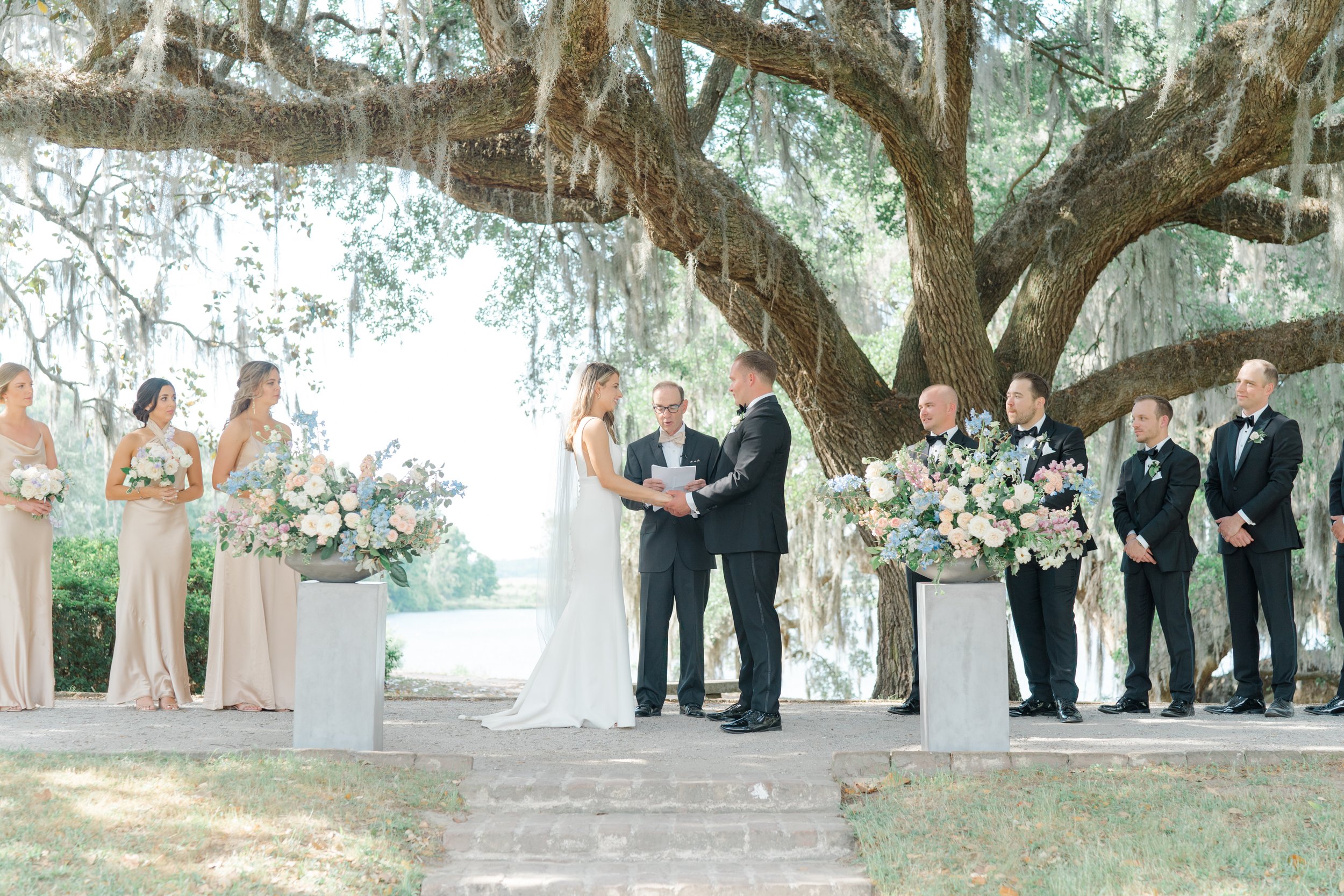 Bride and groom hold hands under live oak tree and spanish moss at Middleton Place spring wedding.