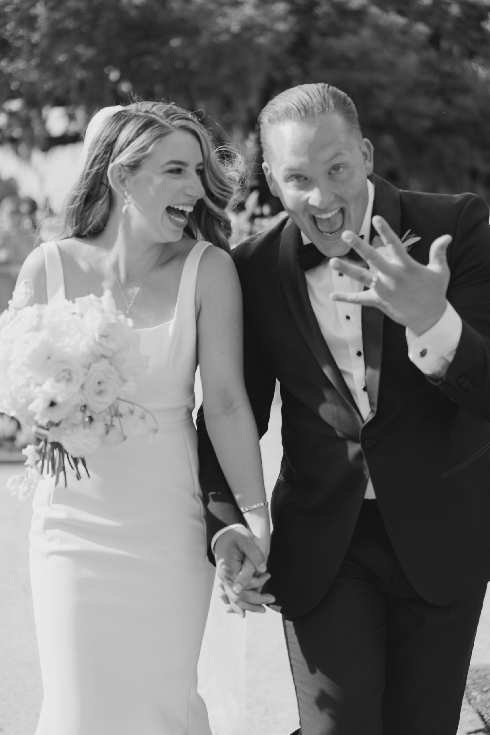 Black and white wedding photo. Groom shows off new ring after outdoor wedding ceremony.