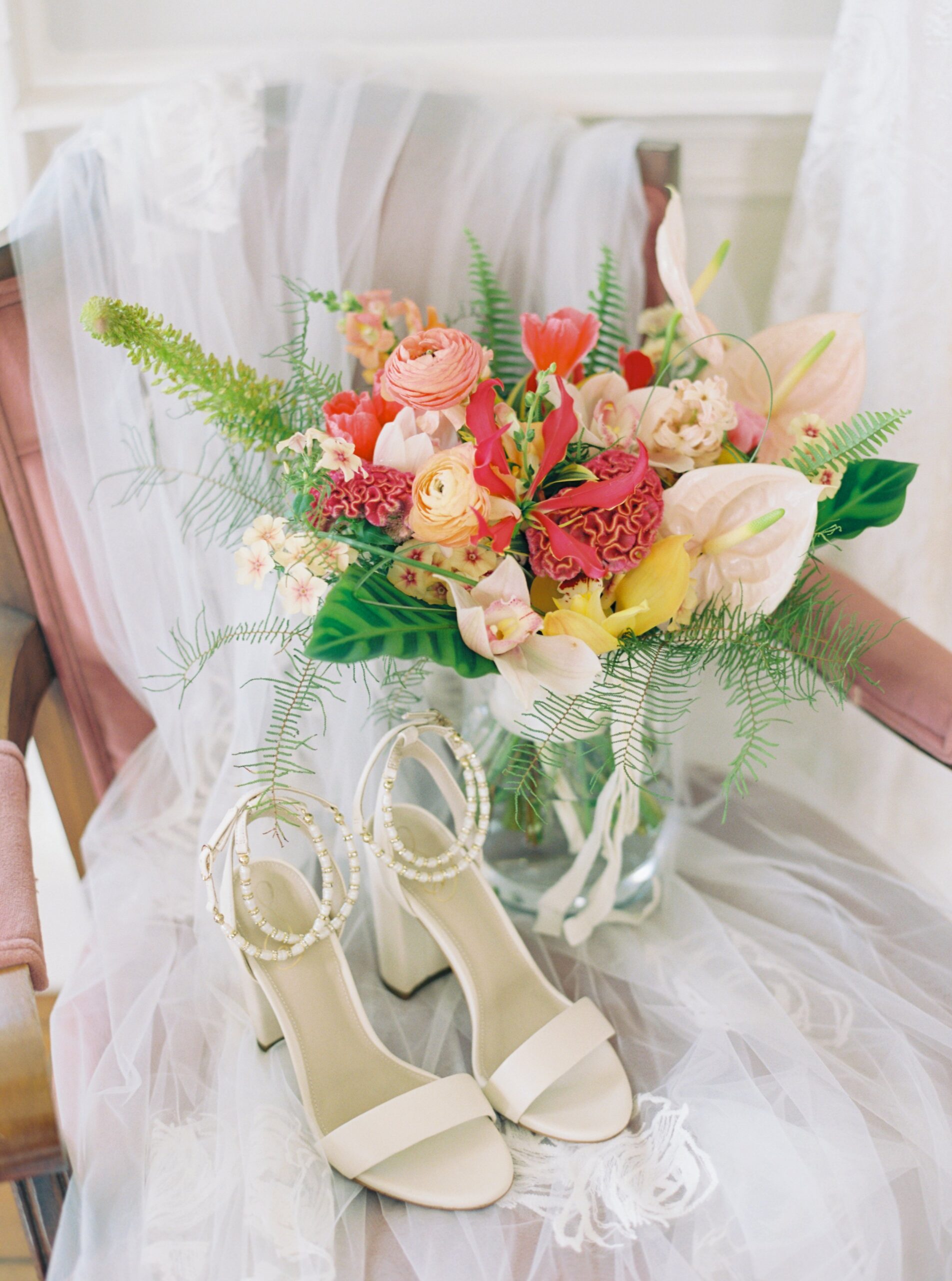 Bridal bouquet and heels laying on veil.