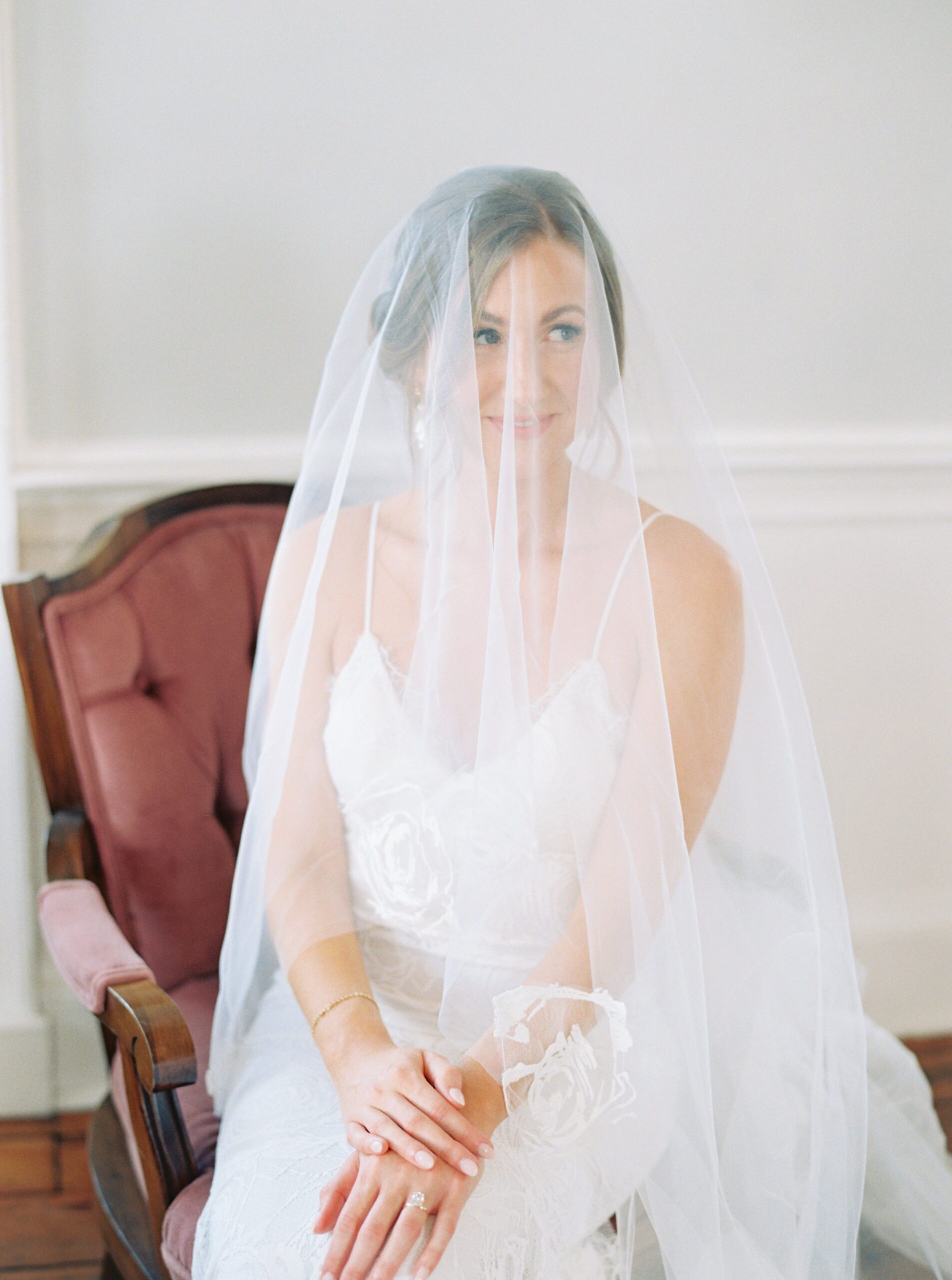 Quiet moment with bride in vintage chair, covered by veil.