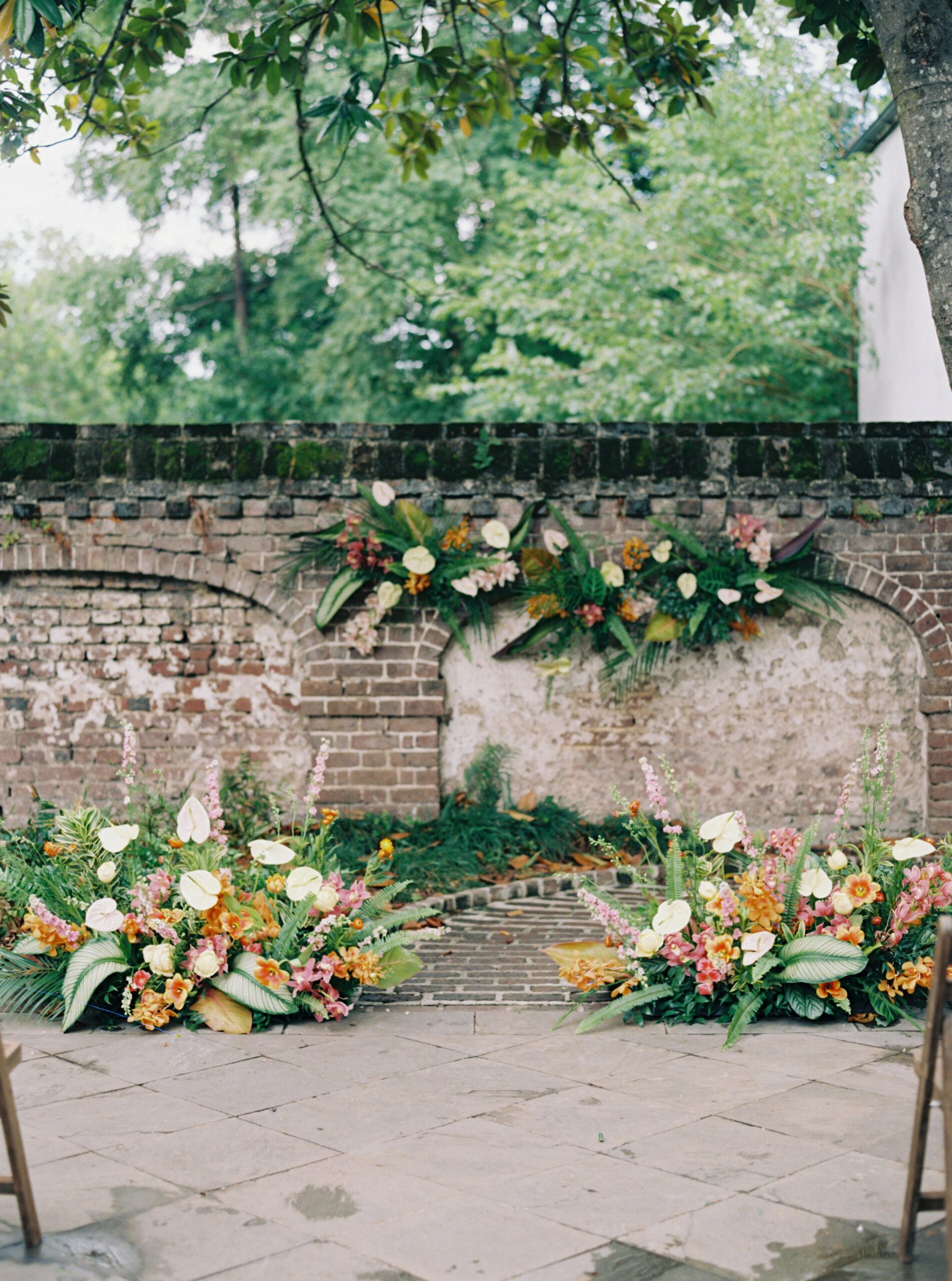Tropical flowers ceremony set up with lush greenery at Gadsden House wedding venue in Charleston SC.