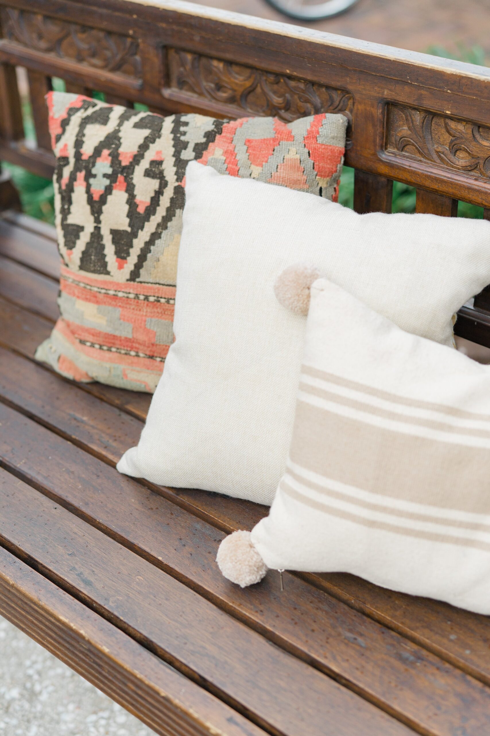 Boho pillows and wooden bench at outdoor wedding reception.