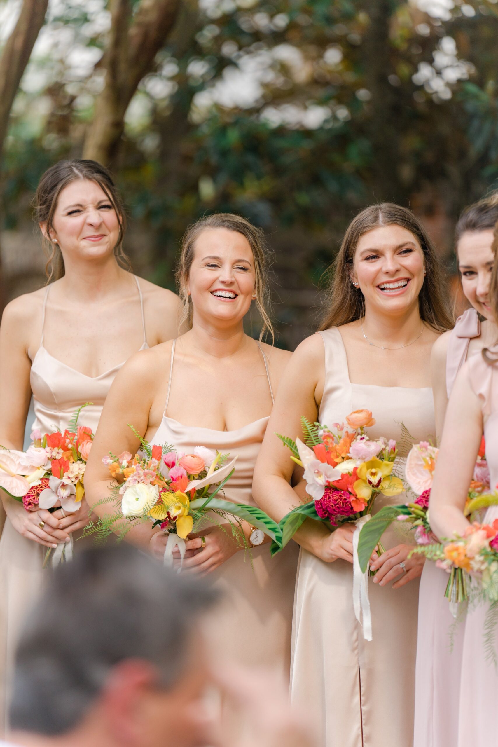 Bridesmaids with tropical flowers laugh during Gadsden House wedding.