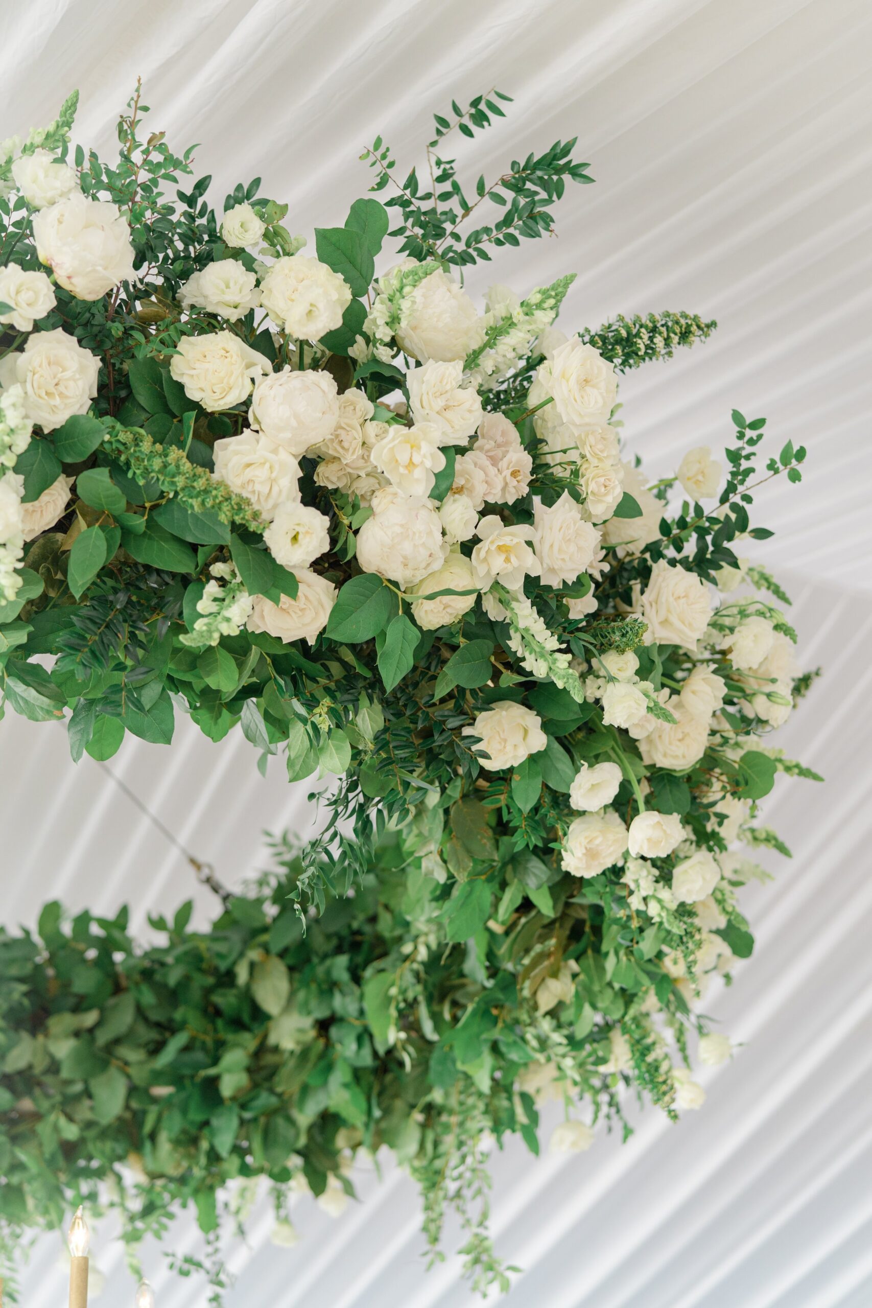 Hanging white flowers and greenery wedding reception installation.