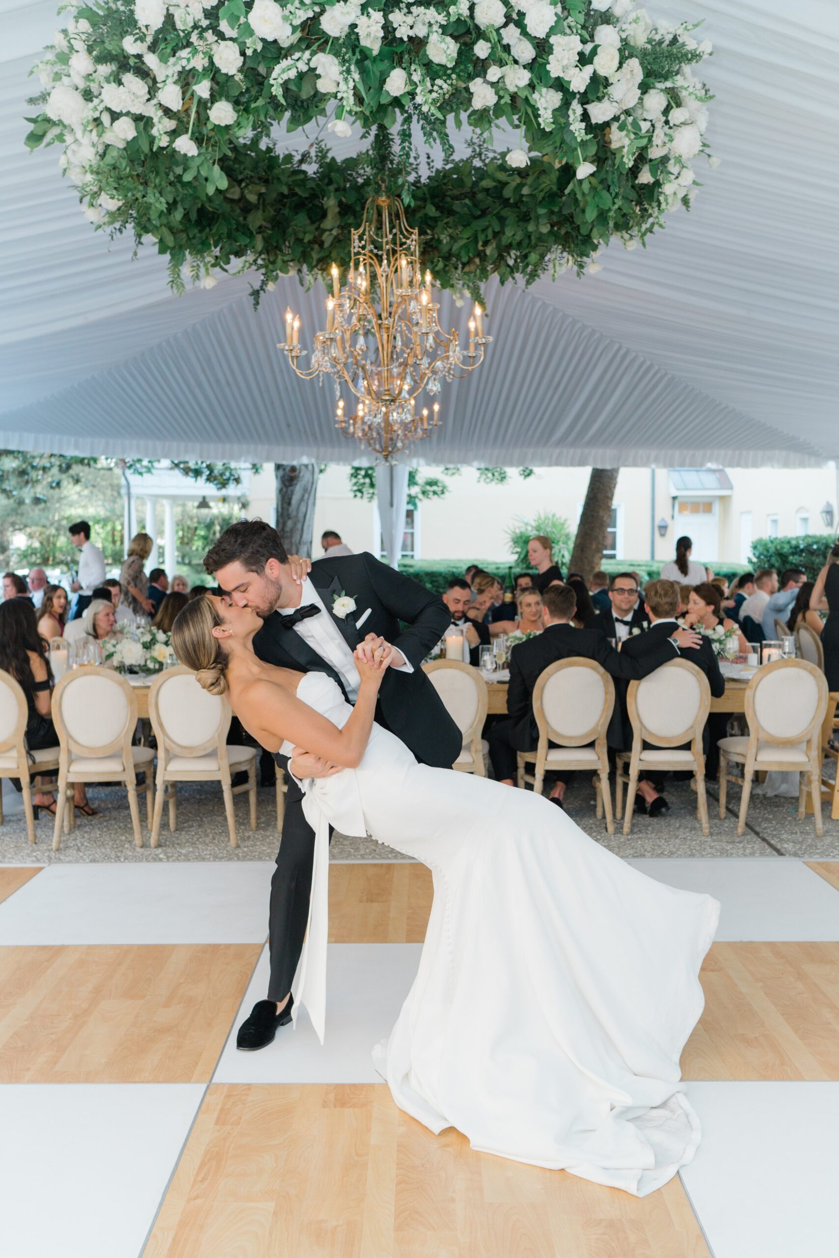 Bride and groom dip kiss with flower chandelier at outdoor Charleston wedding reception. East Coast Destination Wedding Photographer.