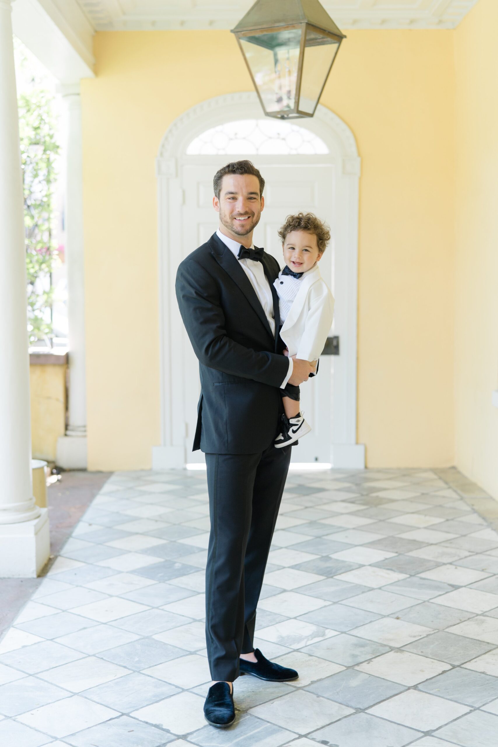 Groom with young sun in white suit jacket and bowtie.