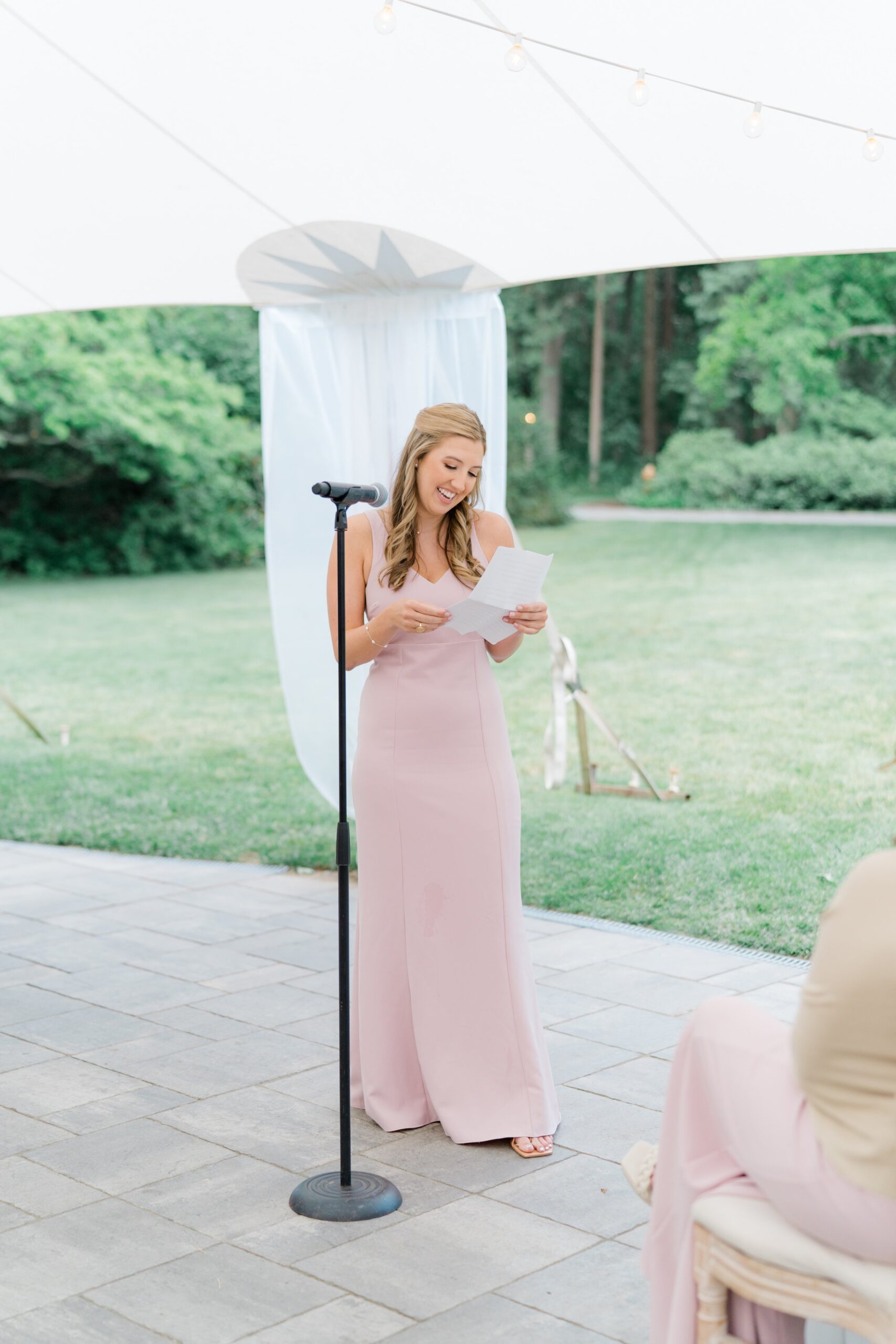 Maid of honor smiles while giving heartfelt speech at summer wedding in boston.