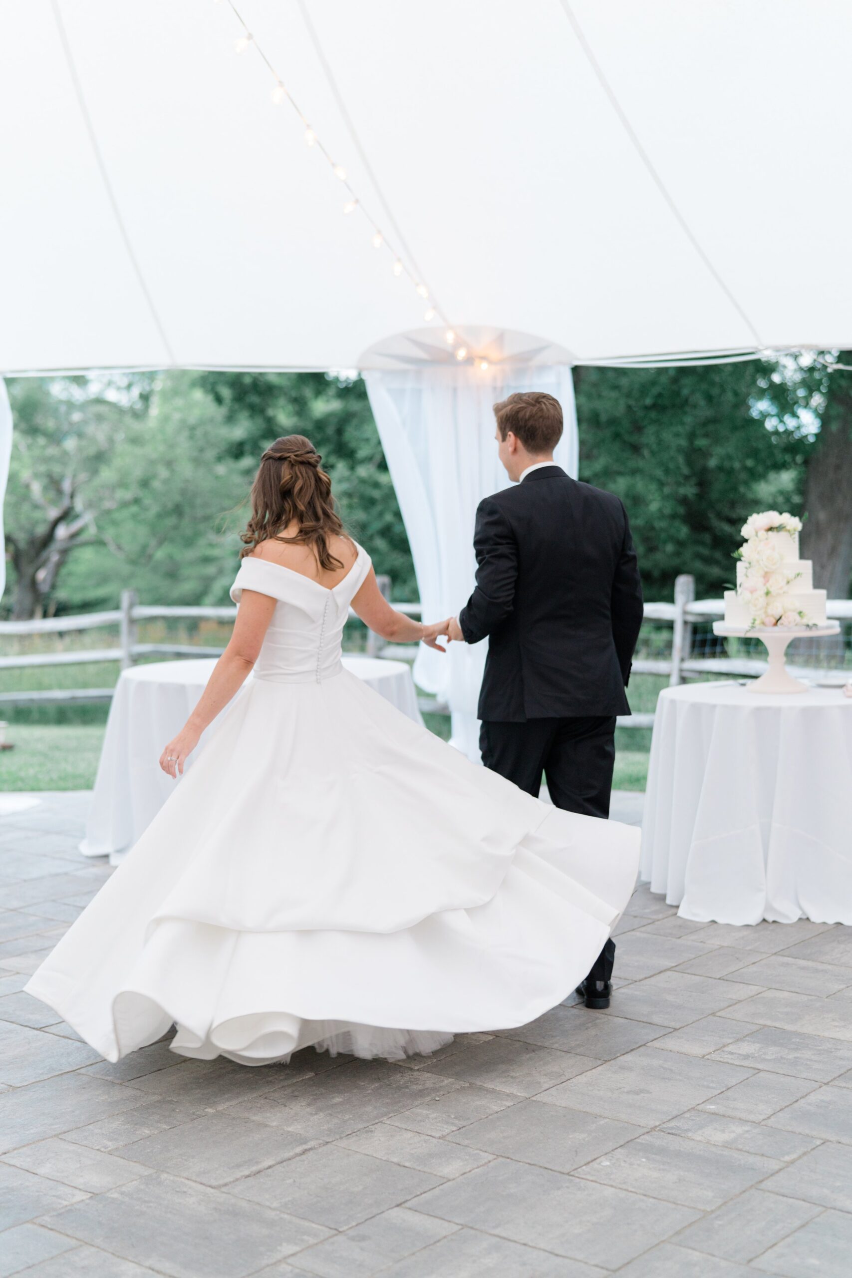 bride twirls her dress while walking at wedding reception.