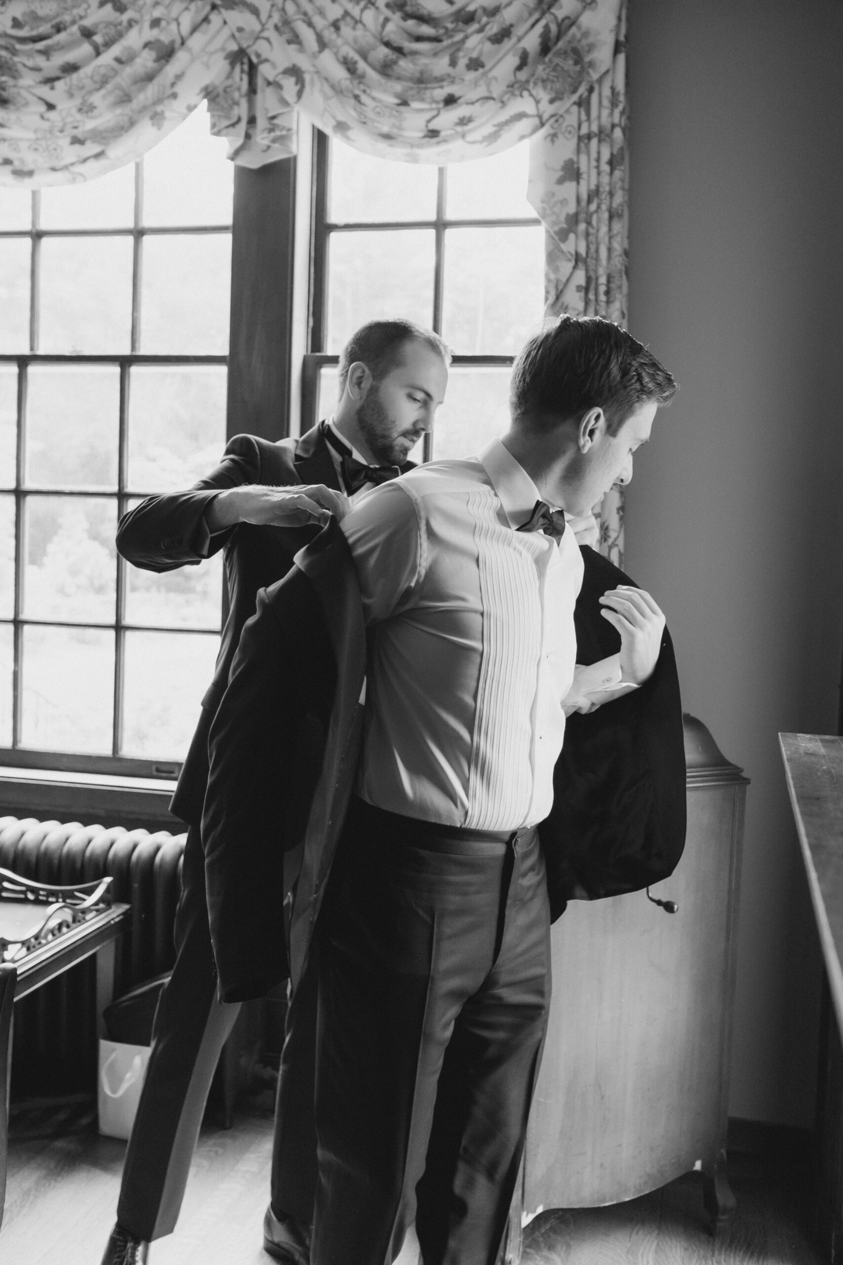 Best man helps groom put on jacket at Bradley Estate Wedding