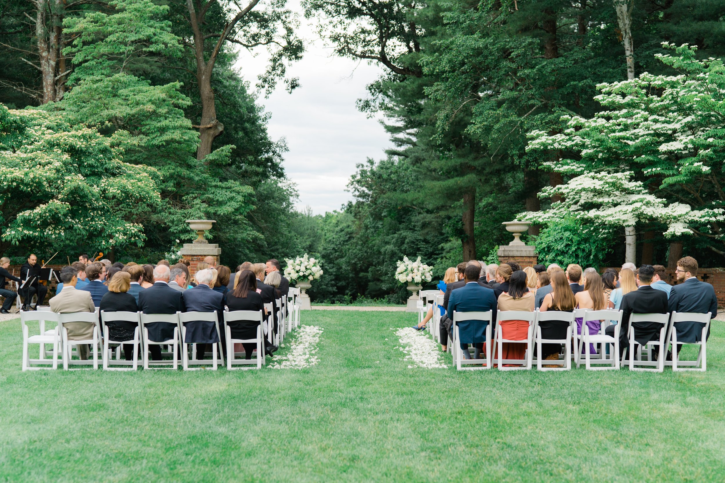 Bradley Estate wedding ceremony with white floral petal lined aisle. Lush greenery at boston summer wedding.