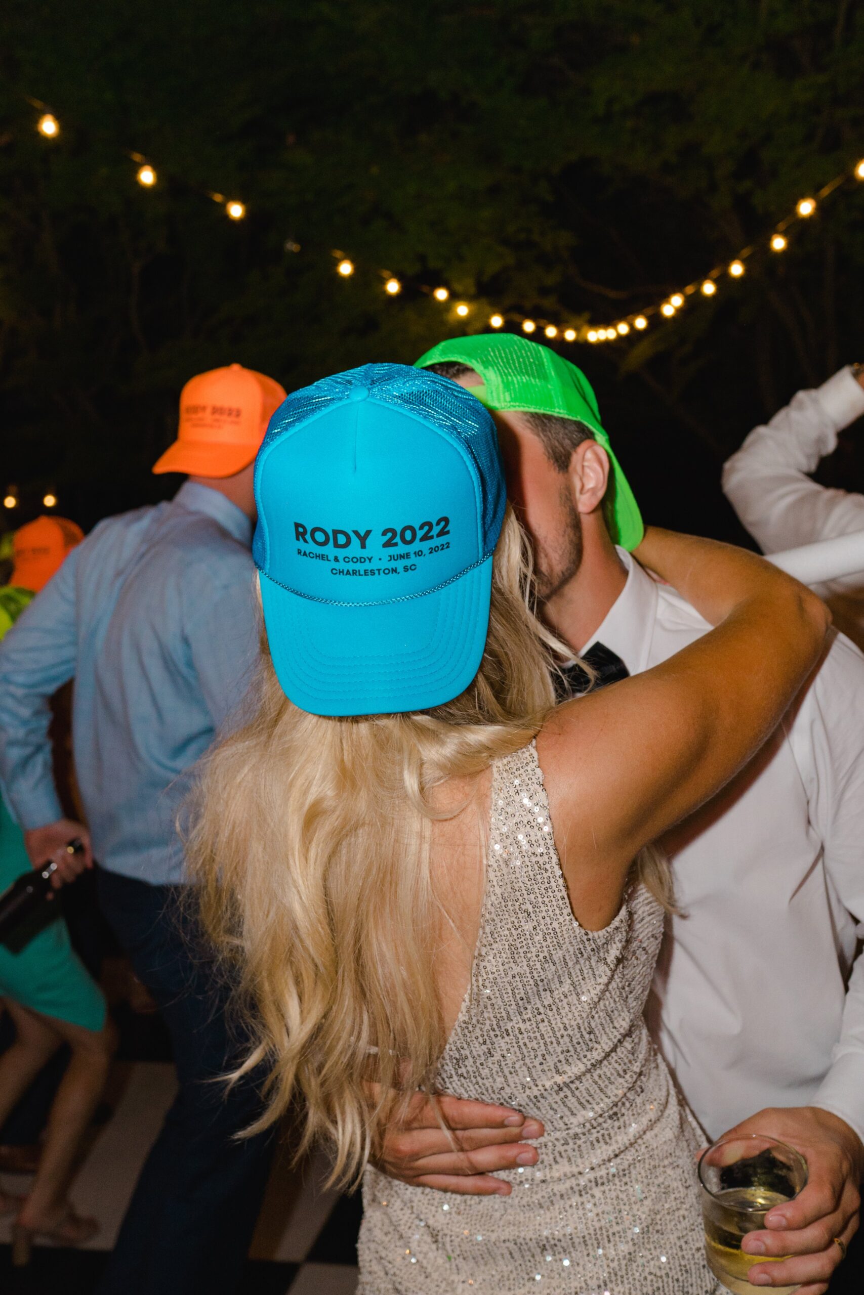 custom neon party hats on the dance floor at outdoor wedding reception.