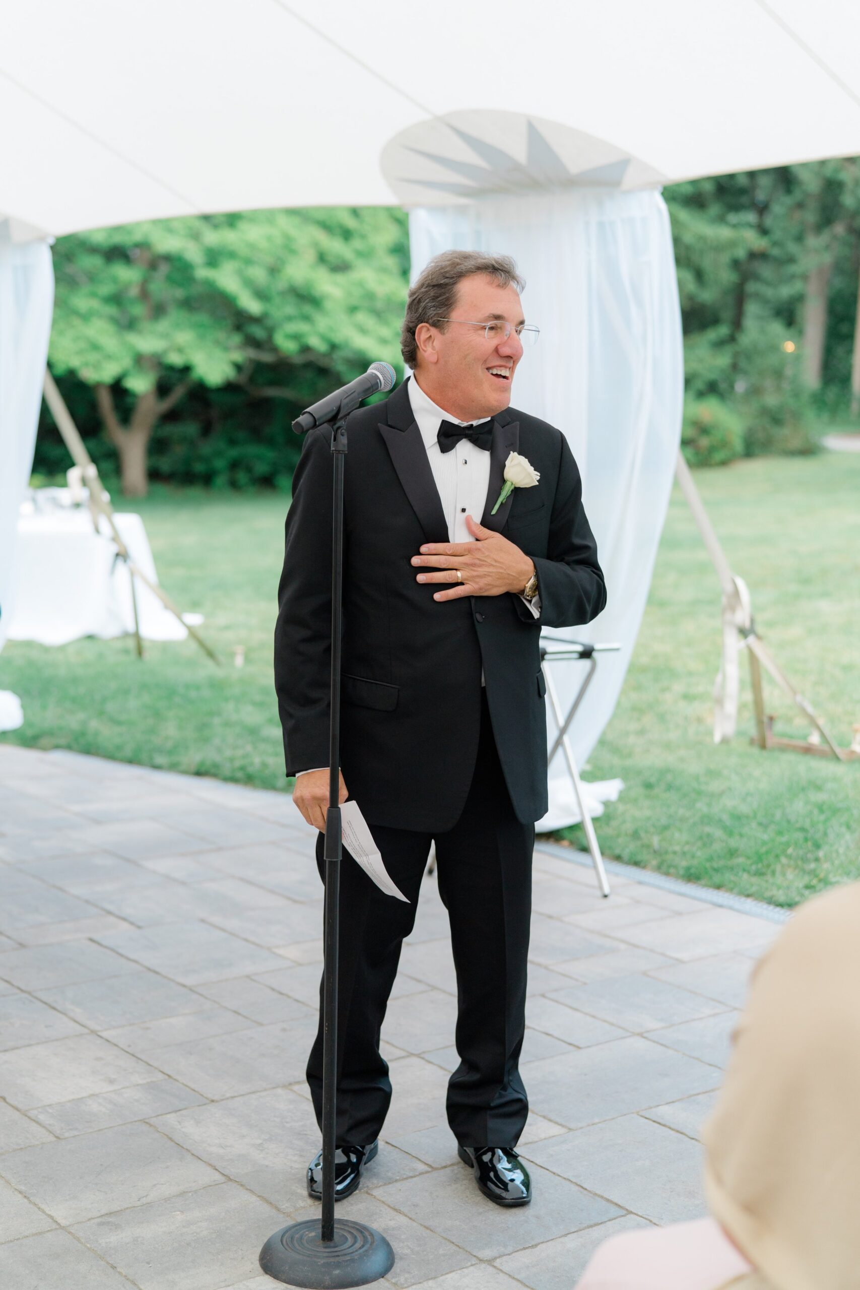 Father of the bride makes emotional speech while holding his chest.