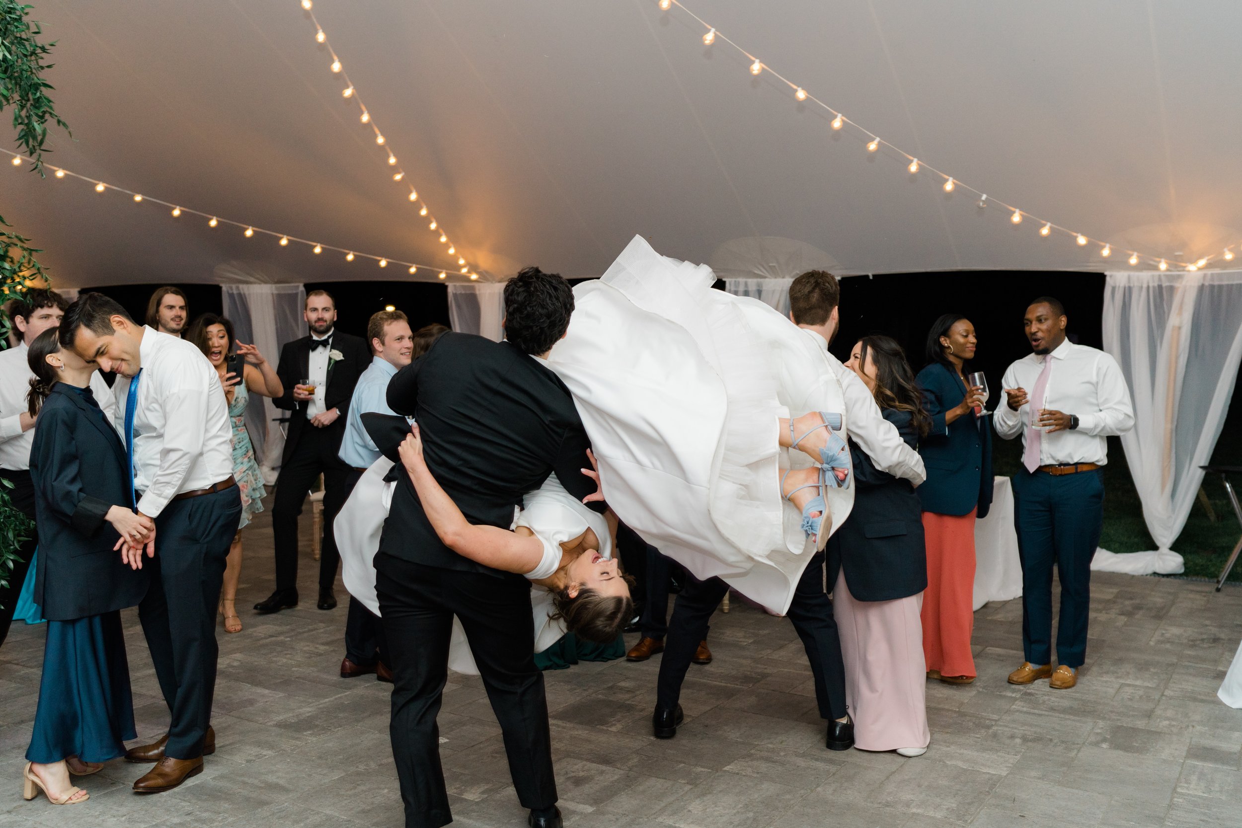 Wedding guest flips bride unexpectedly during dance at outdoor wedding reception in Boston. showing off blue randall loeffler heels.