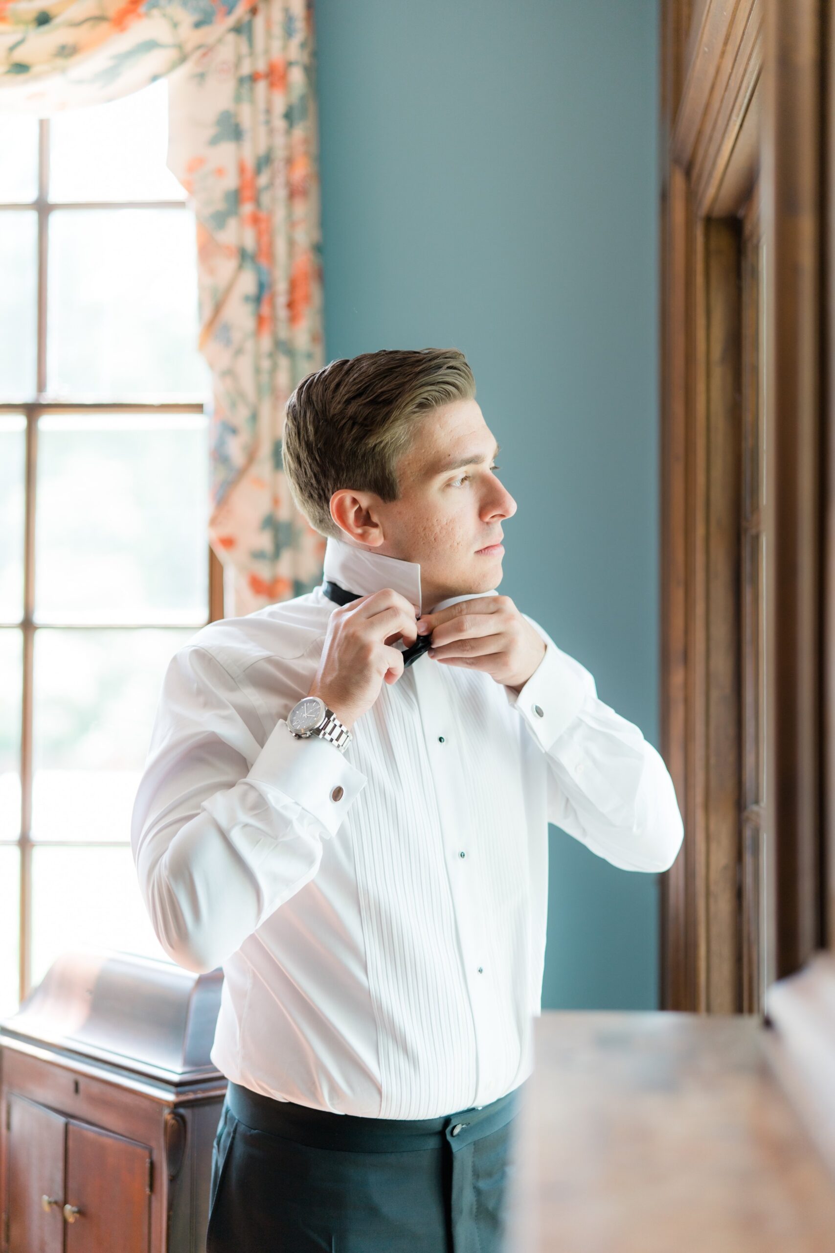 Groom adjusts bow tie on the morning of wedding at the Bradley Estate.
