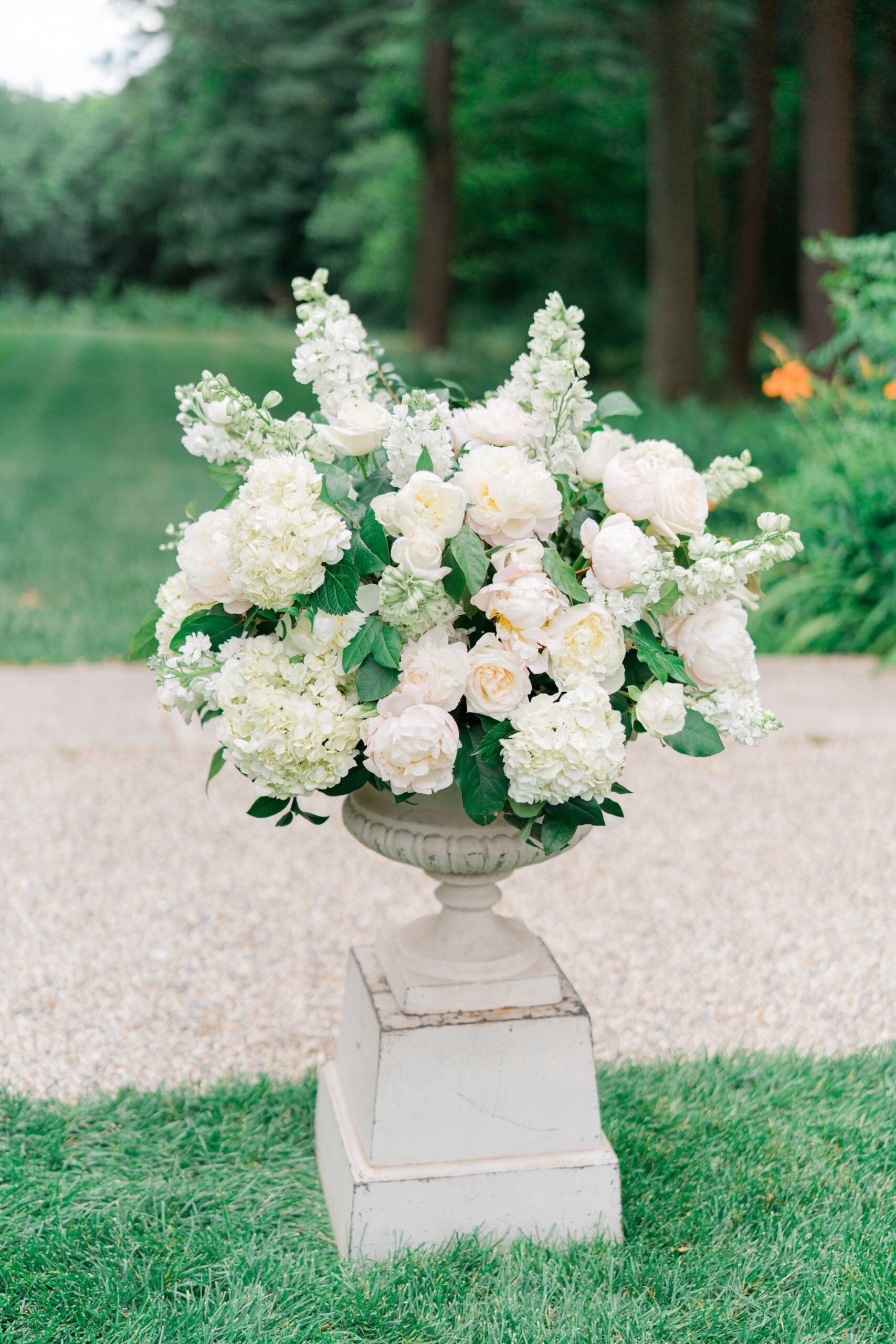 Lush white and green florals in stone pedestal. At boston wedding ceremony