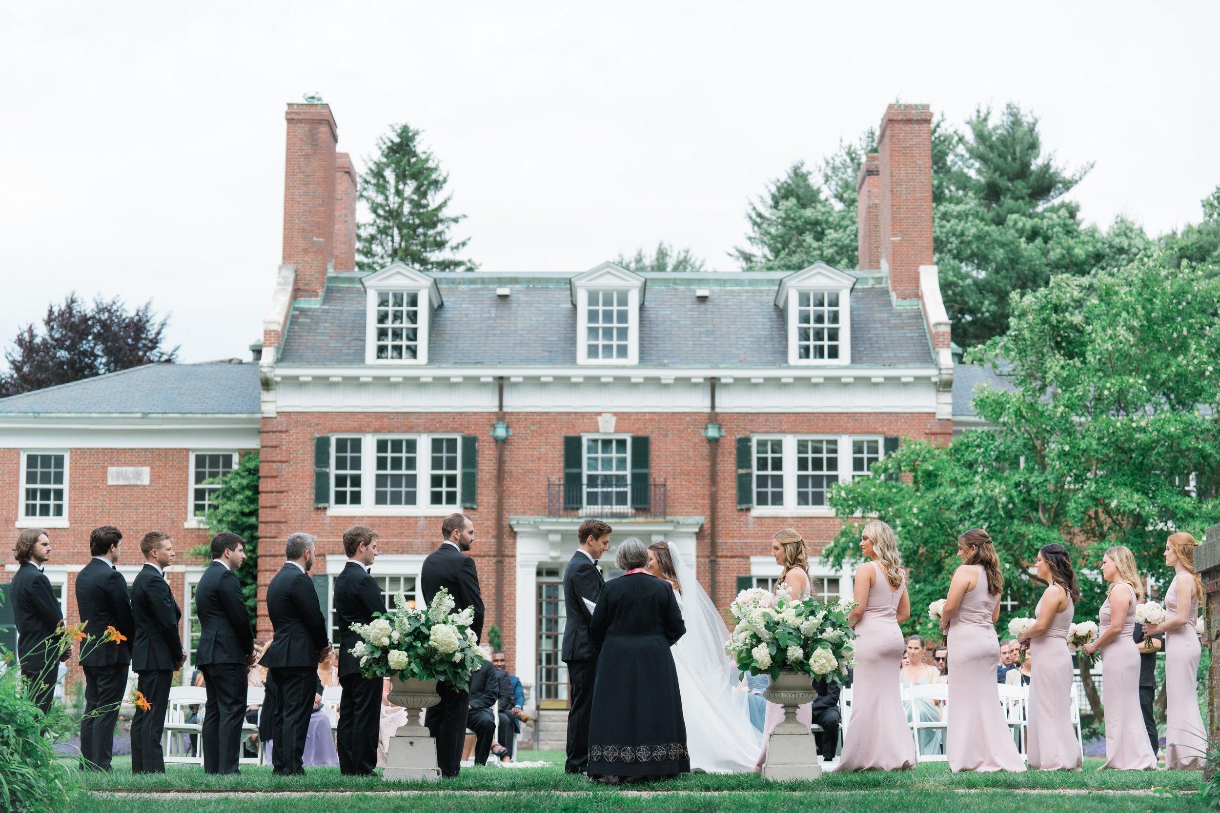 Expansive overall picture of the full bridal party during summer wedding ceremony at the Bradley Estate in Suburban Boston.