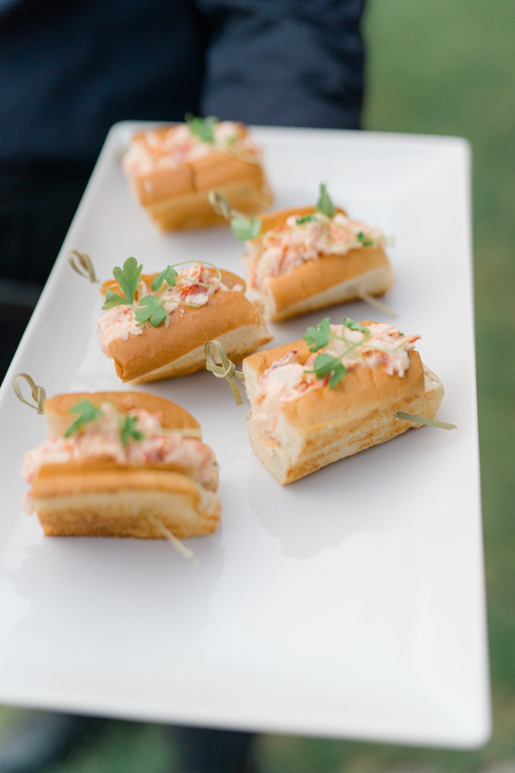 Lobster rolls served at cocktail hour for New England outdoor wedding reception.
