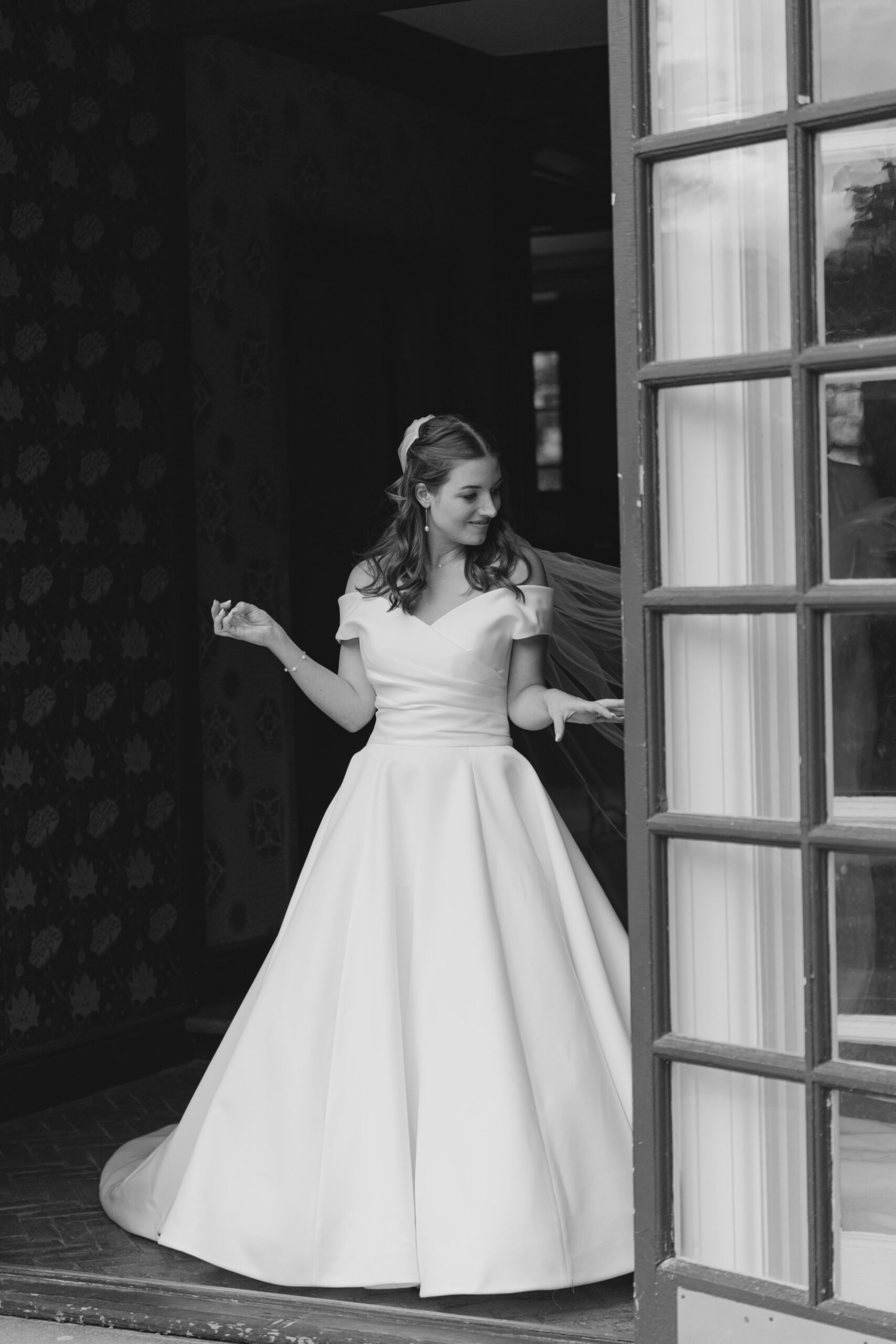 Candid black and white moment while bride gets dress bustled at boston summer wedding.