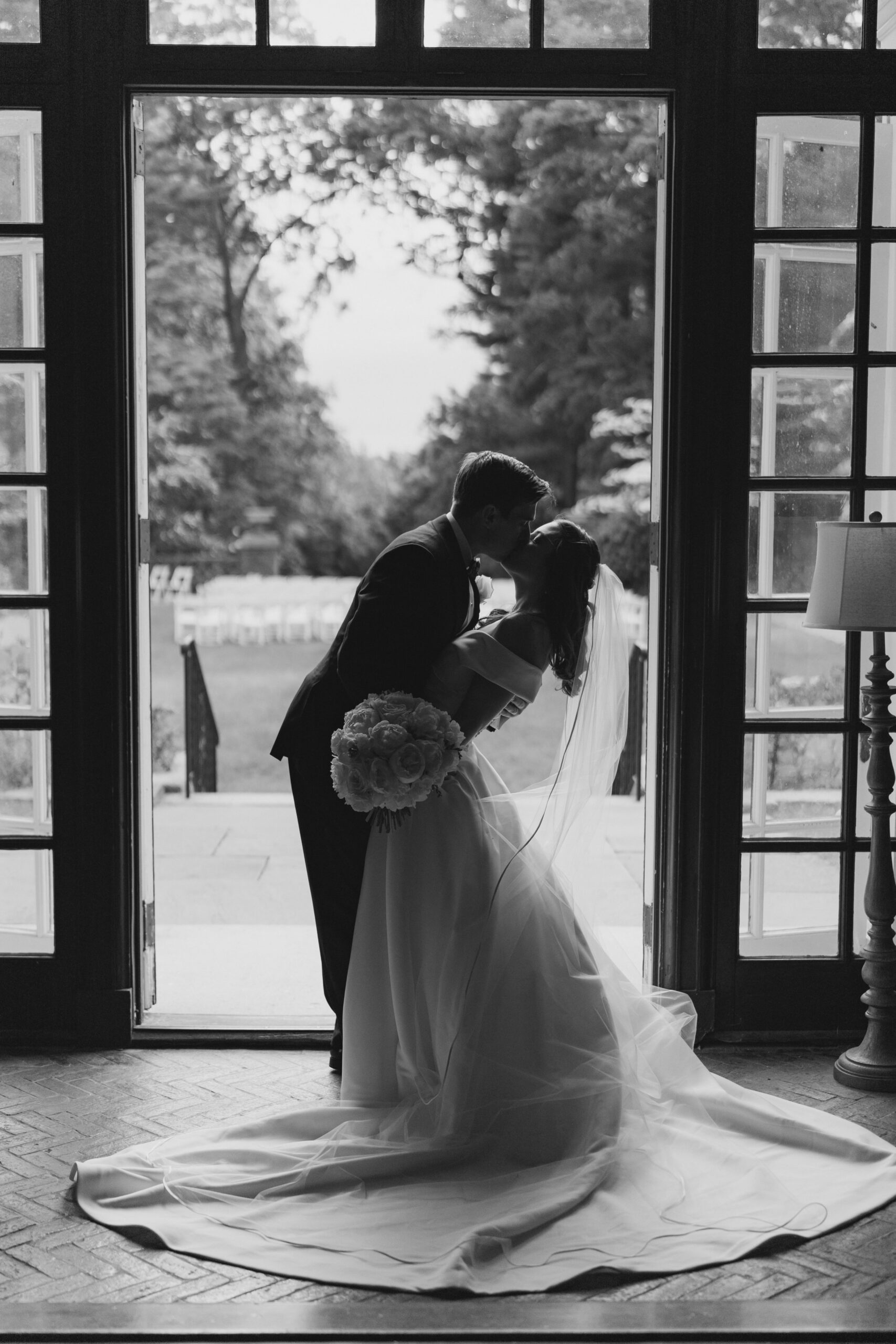 dramatic black and white dip kiss between bride and groom in the doorway at the Bradley Estate. Summer wedding in Boston.