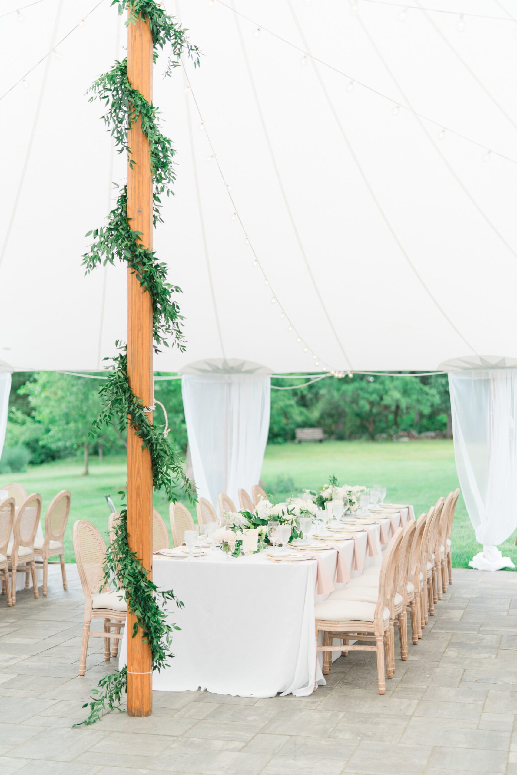 Classic white and green sperry tent reception with wooden pole wrapped in lush greenery. Boston summer wedding.
