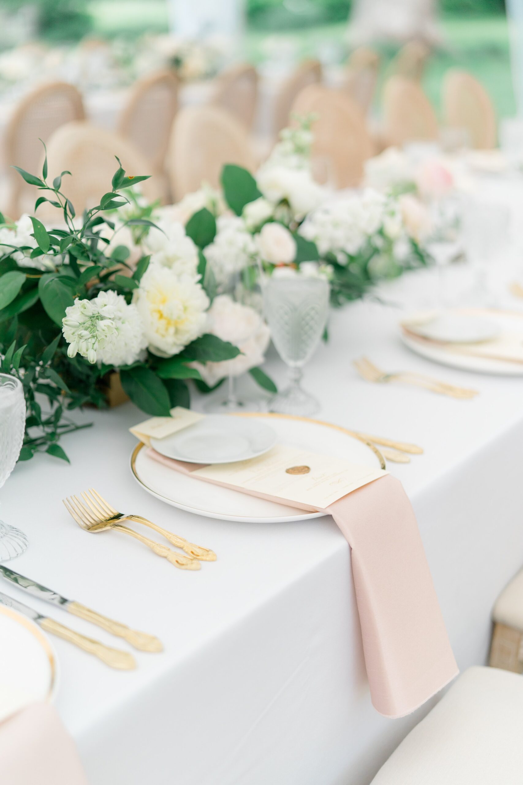 Pale pink table napkins with golden utensils and gold rimmed plates.