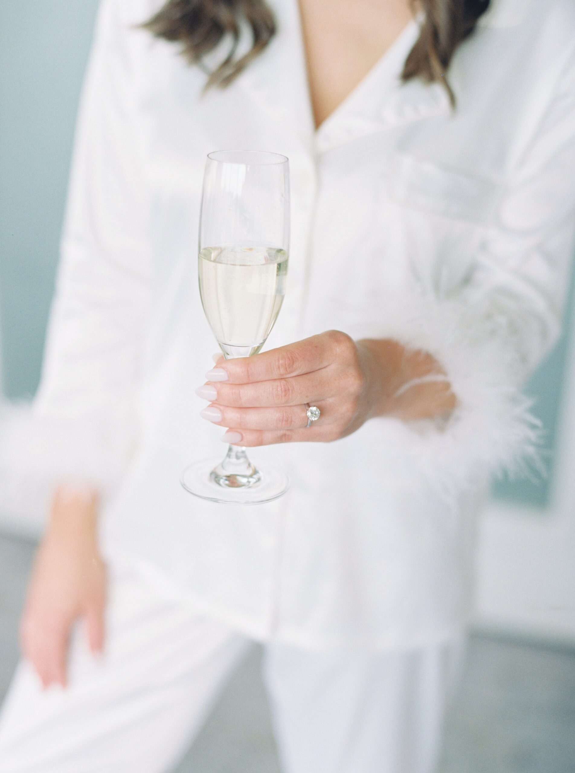 Bride holding champagne flute with her engagement ring hand