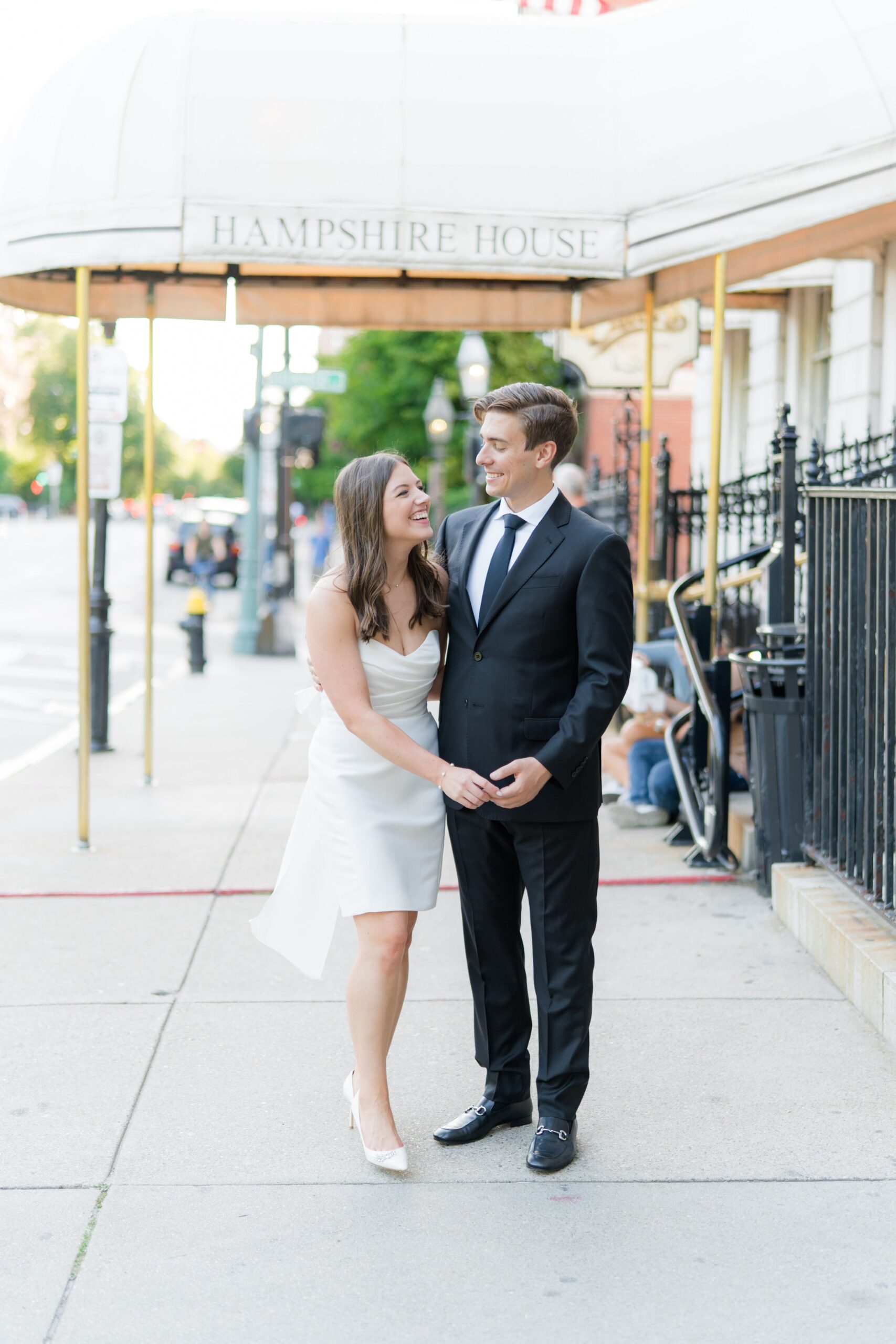 Fun moment between future bride and groom on the sidewalk in front of hampshire house near boston common.