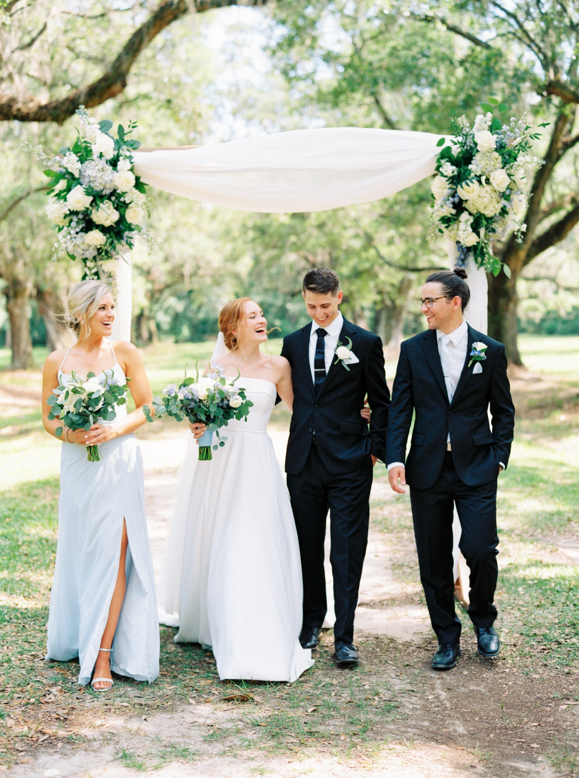 bridal party walks together under live oak trees at spring outdoor wedding.