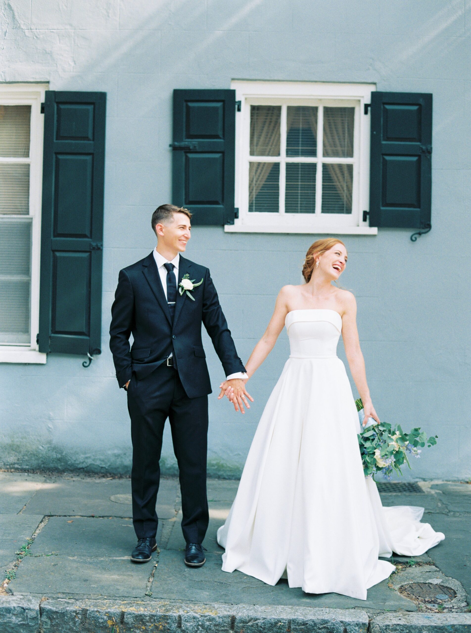 bride and groom laugh with pedestrians walking by during downtown Charleston wedding portraits.