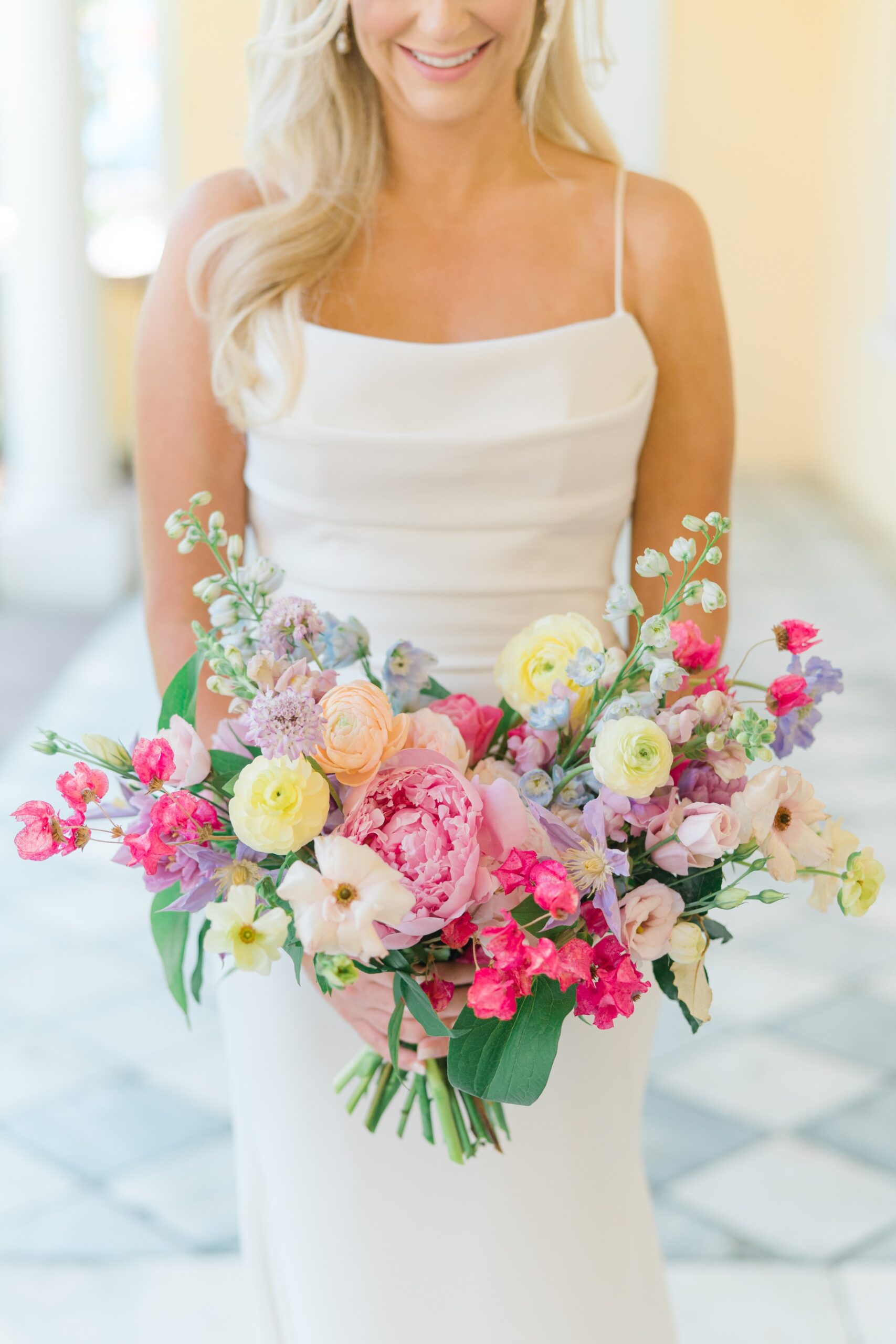 close up of bride holding spring themed asymmetrical flowers. bold pinks with pops of yellow and light purple.
