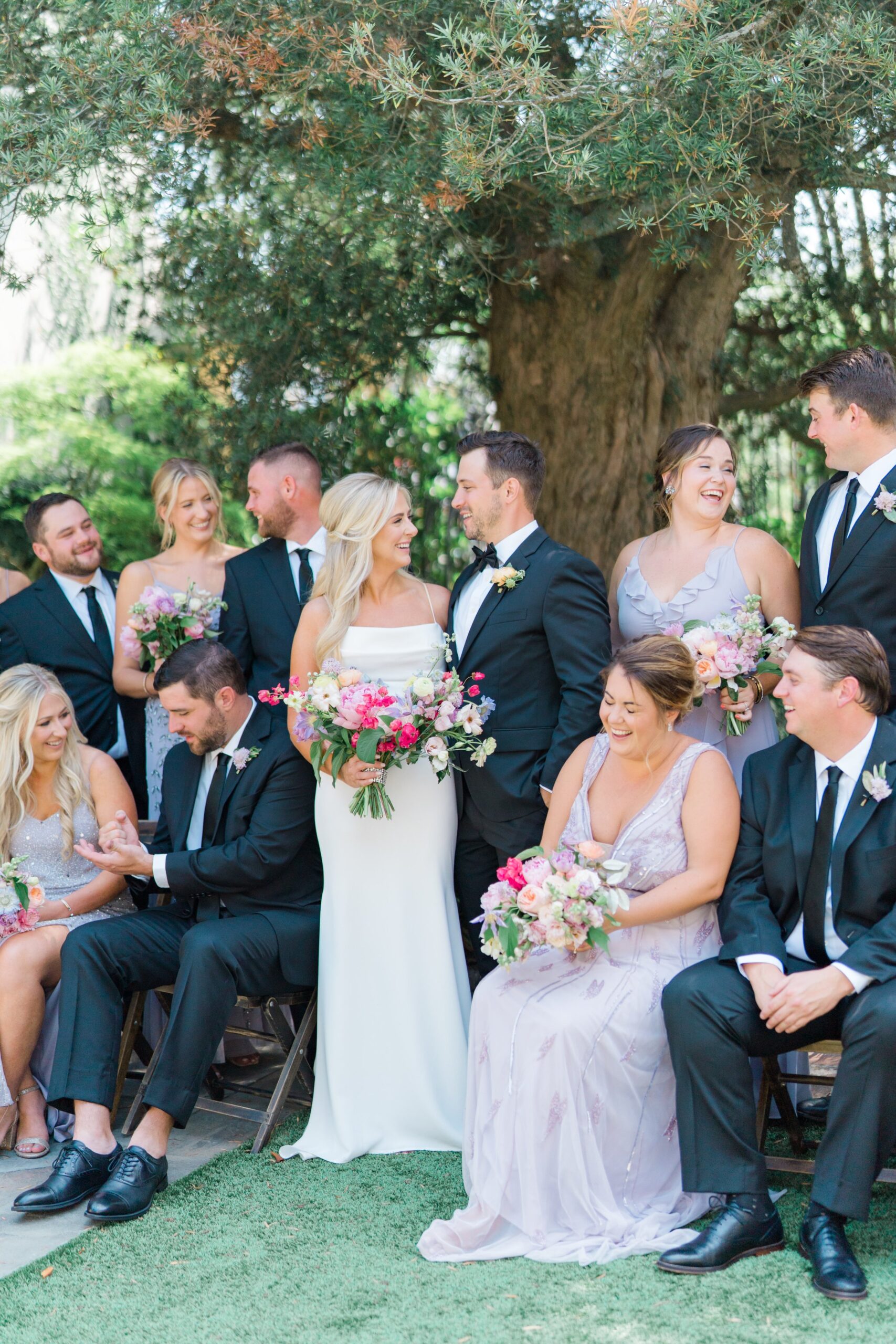 bride and groom laugh towards each other with rest of bridal party with spring wedding.