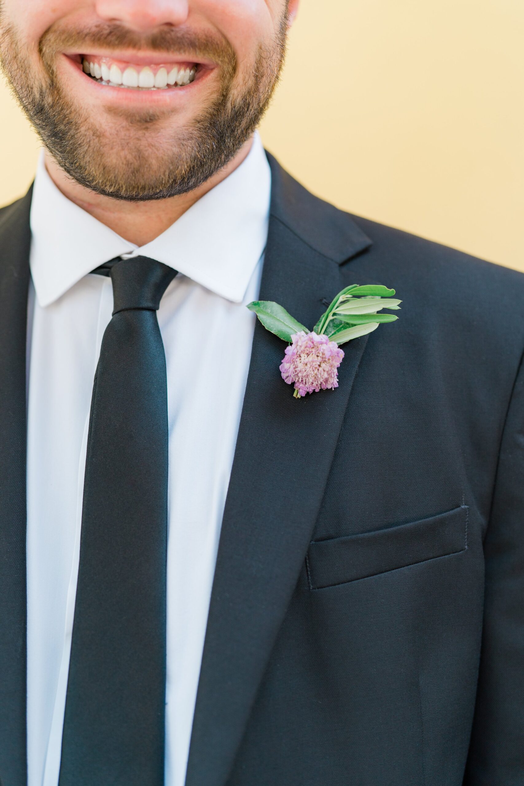 groomsman in black tie and light purple boutonniere