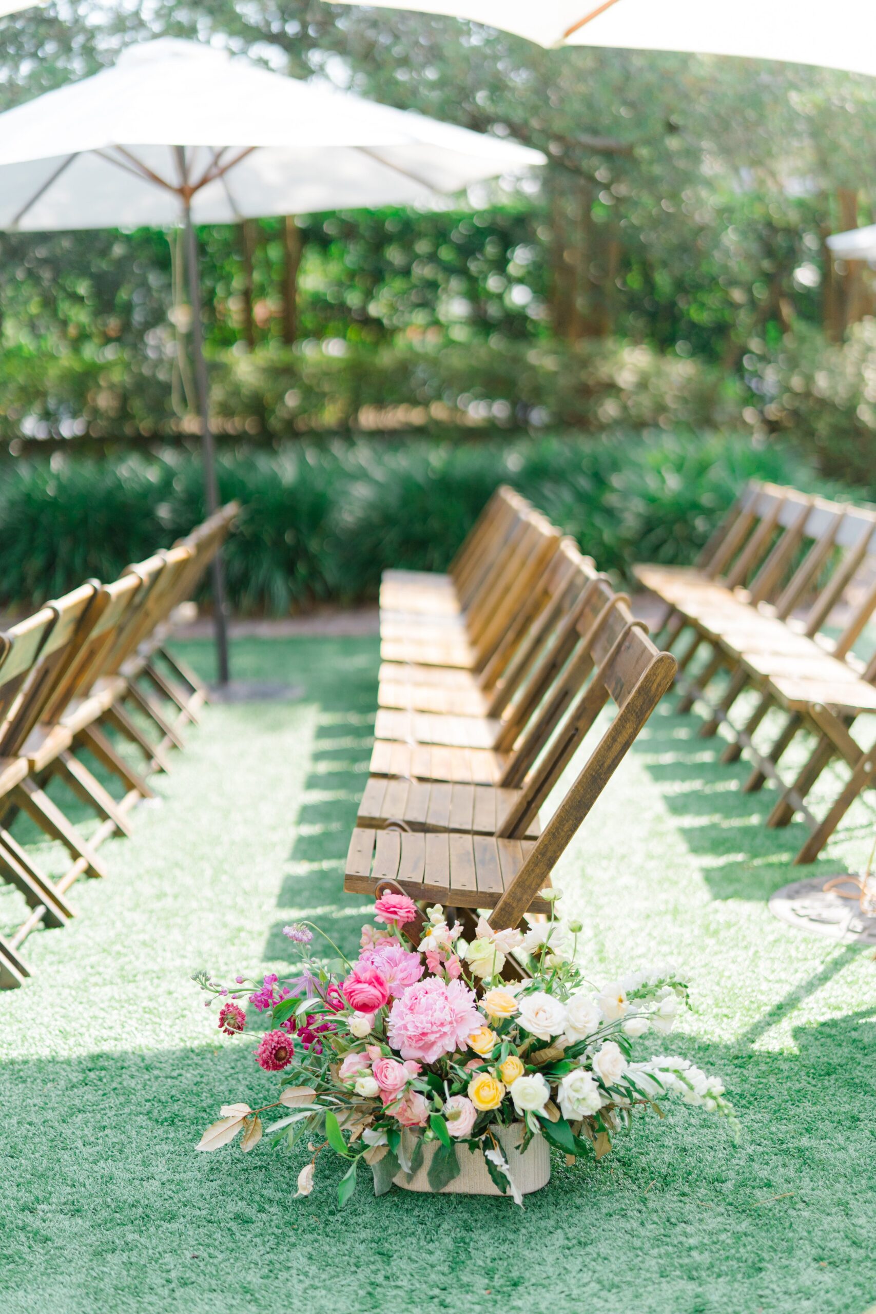 wedding ceremony aisle flowers with wooden chairs.