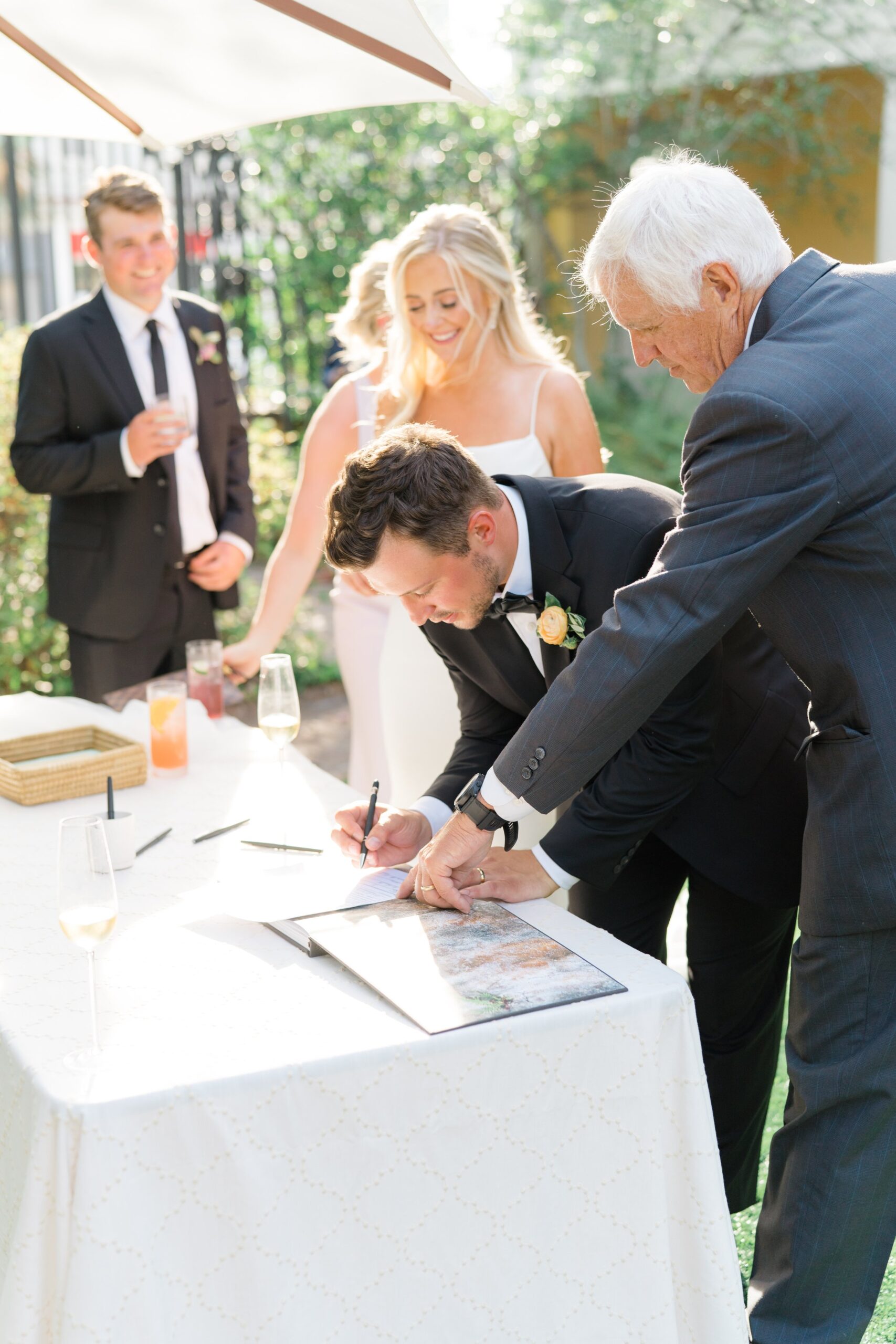 bride and groom sign marriage license and laugh with officiant