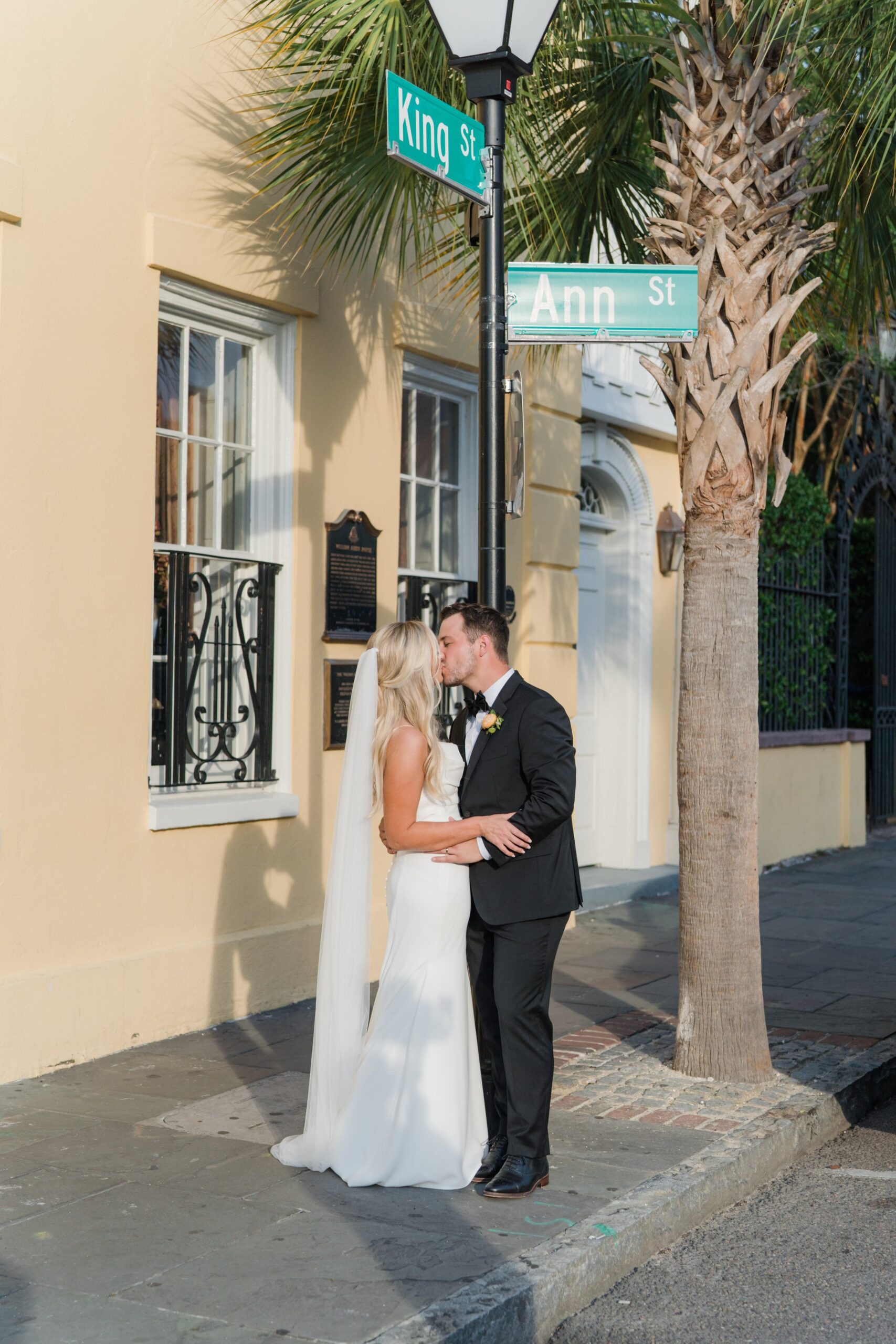 full sun bride and groom wedding portrait on the sidewalk with william aiken house and palm tree.