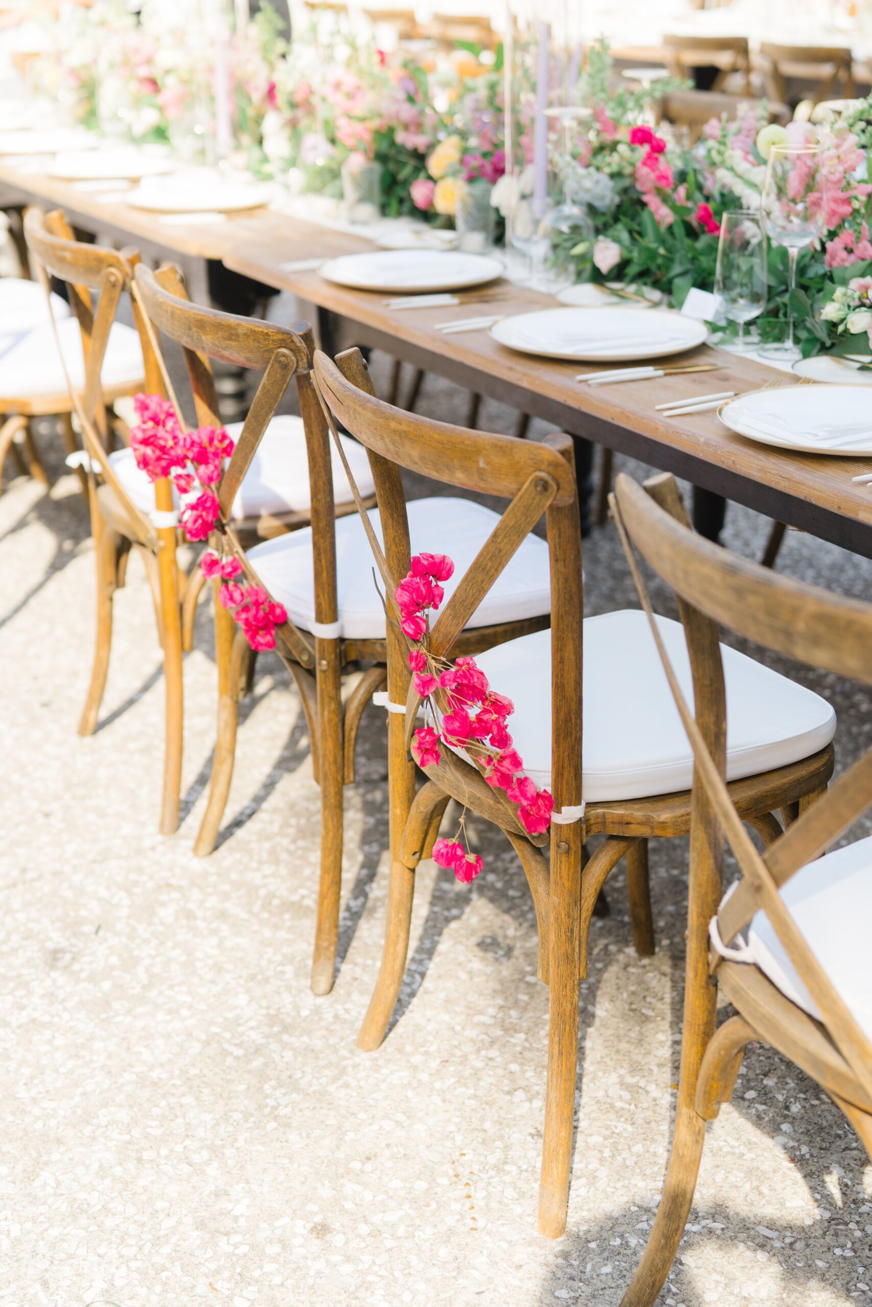 pink flowers accent bride and groom chairs for head table at outdoor al fresco wedding reception dinner.